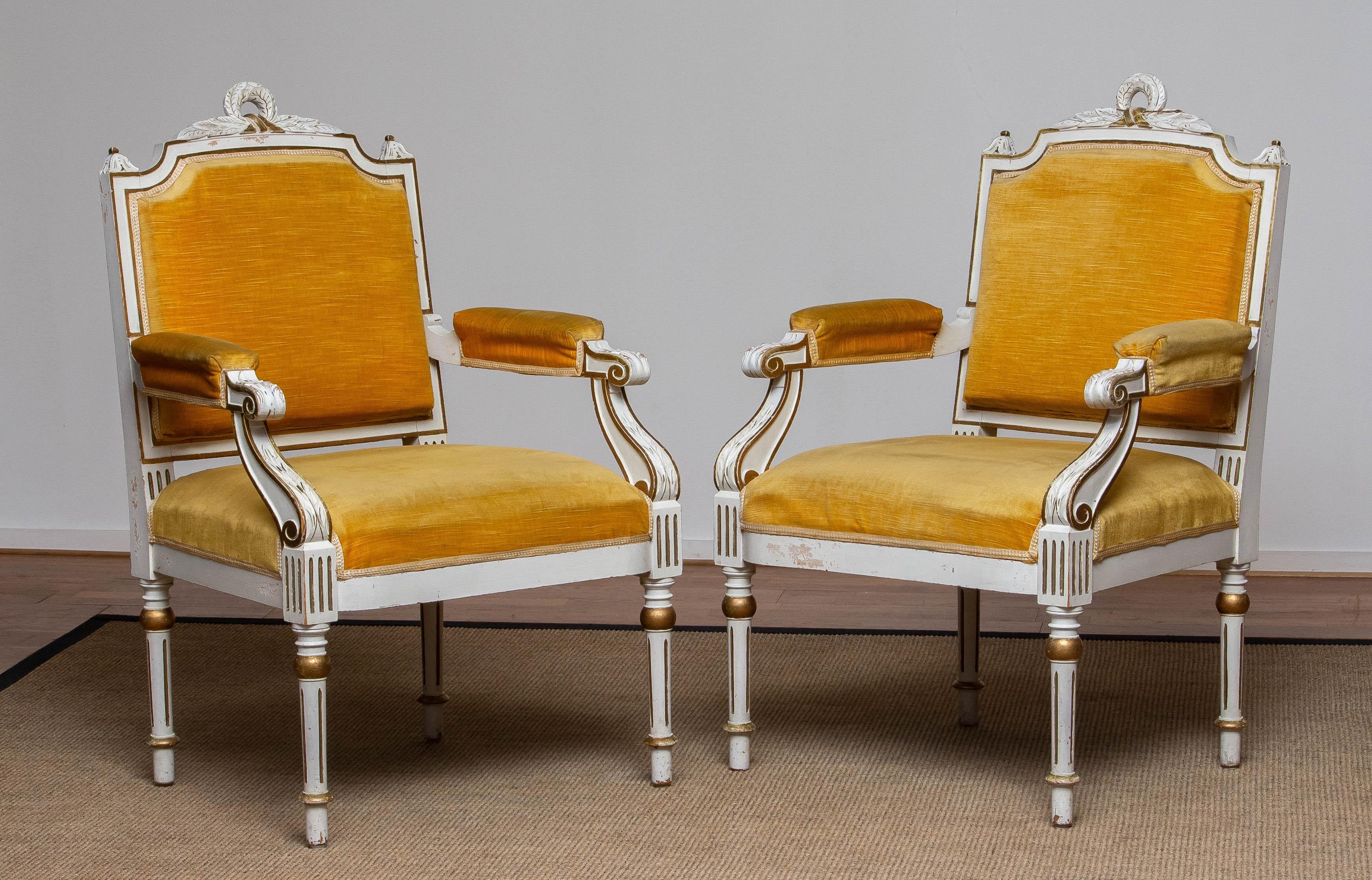 Very rich decorative set of 18th century white Louis XVI armchairs with gilded and painted details.
Both wooden frames are in good condition. The gold colored velvet upholstery is from a much later period and upholstered over the original