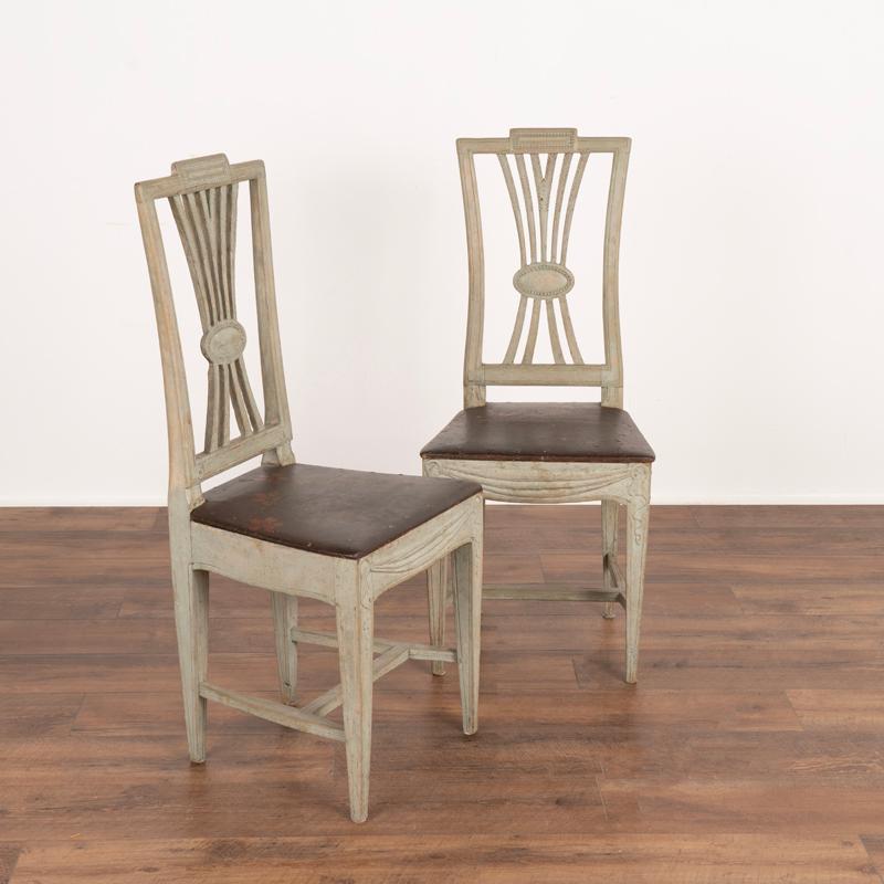 A fine pair of Gustavian side chairs reflecting Sweden’s love of nature seen in the wheat carvings that comprise the back. The original pale green painted finish (with gray undertones) reveals age related wear throughout, adding to the gentle grace