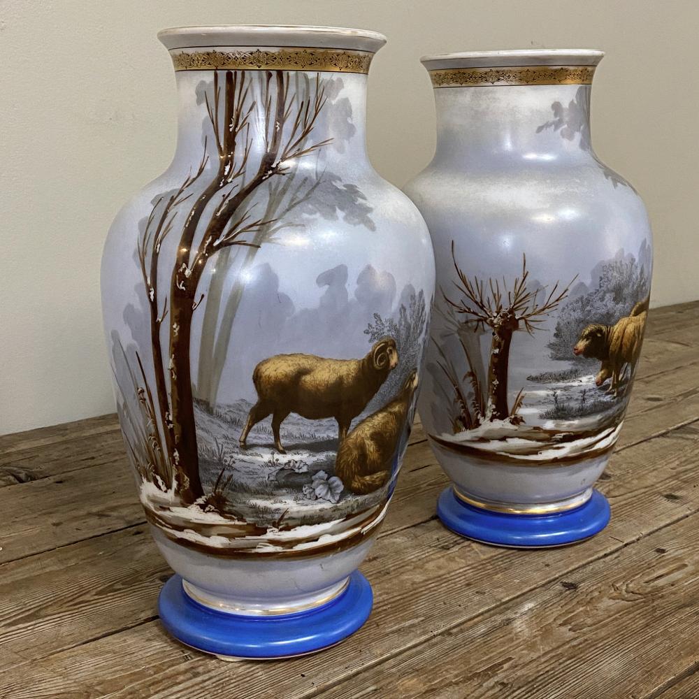Pair of antique hand painted opaline vases will make a delightful addition to your decor, with subtle gray tones in the background and warm browns and golds used to depict mirror images of a ram and ewe in a naturalistic setting. The gold pattern on