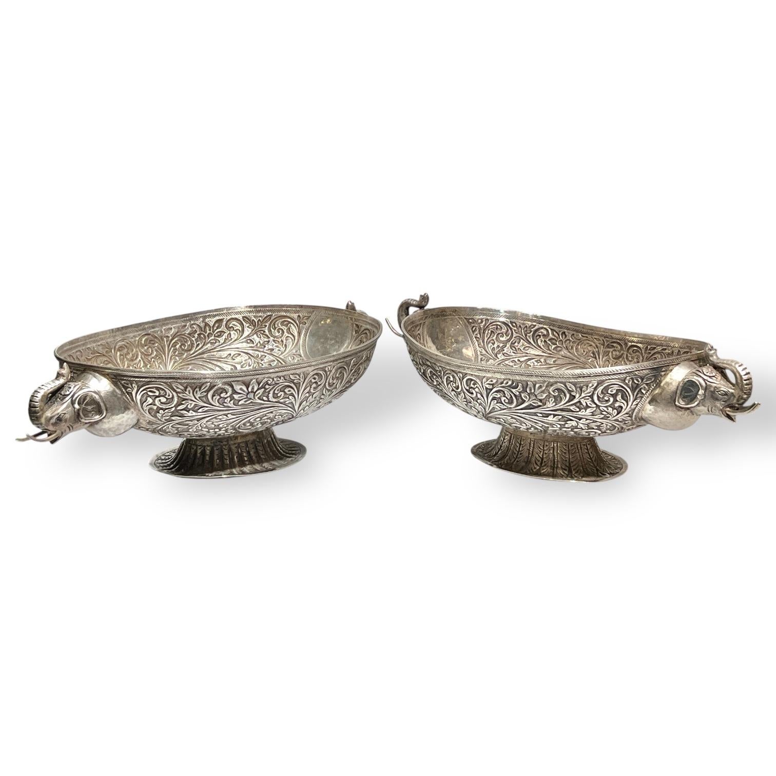 Pair of antique (early 20th century) sterling silver footed centerpiece bowls of ovoid shape and featuring fine chased and repousse designs of scrolling foliage and distinguished by their elephant form handles.  20 by 11 1/4 by 5 and 20 by 10 by 5
