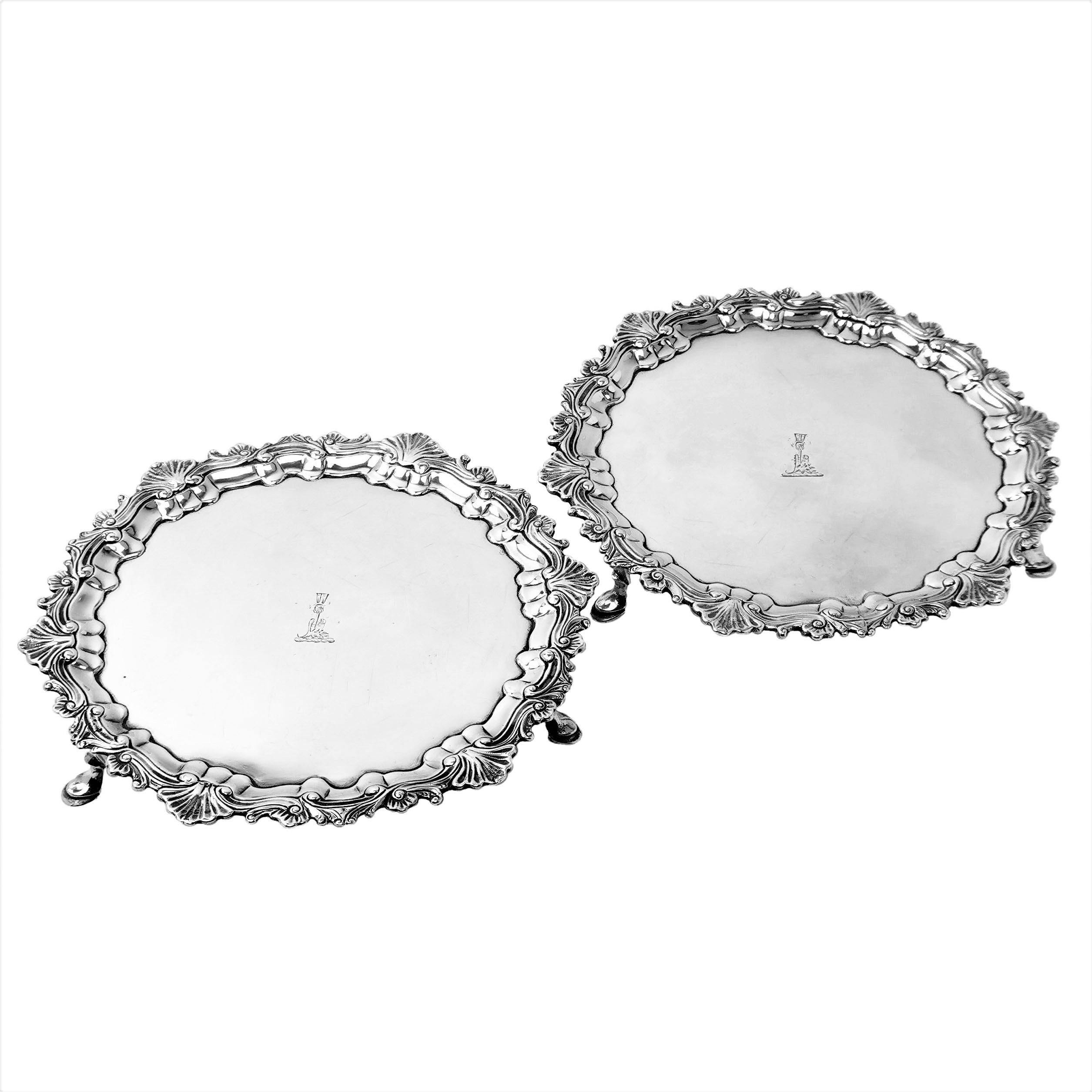 A lovely pair of Antique George III solid silver salvers with classic shell and scroll borders. Each Salver has crest engraved in the centre and stands on three hoof feet. 

Made in Dublin, Ireland in c. 1770 by Charles Townsend.

Approx. Total