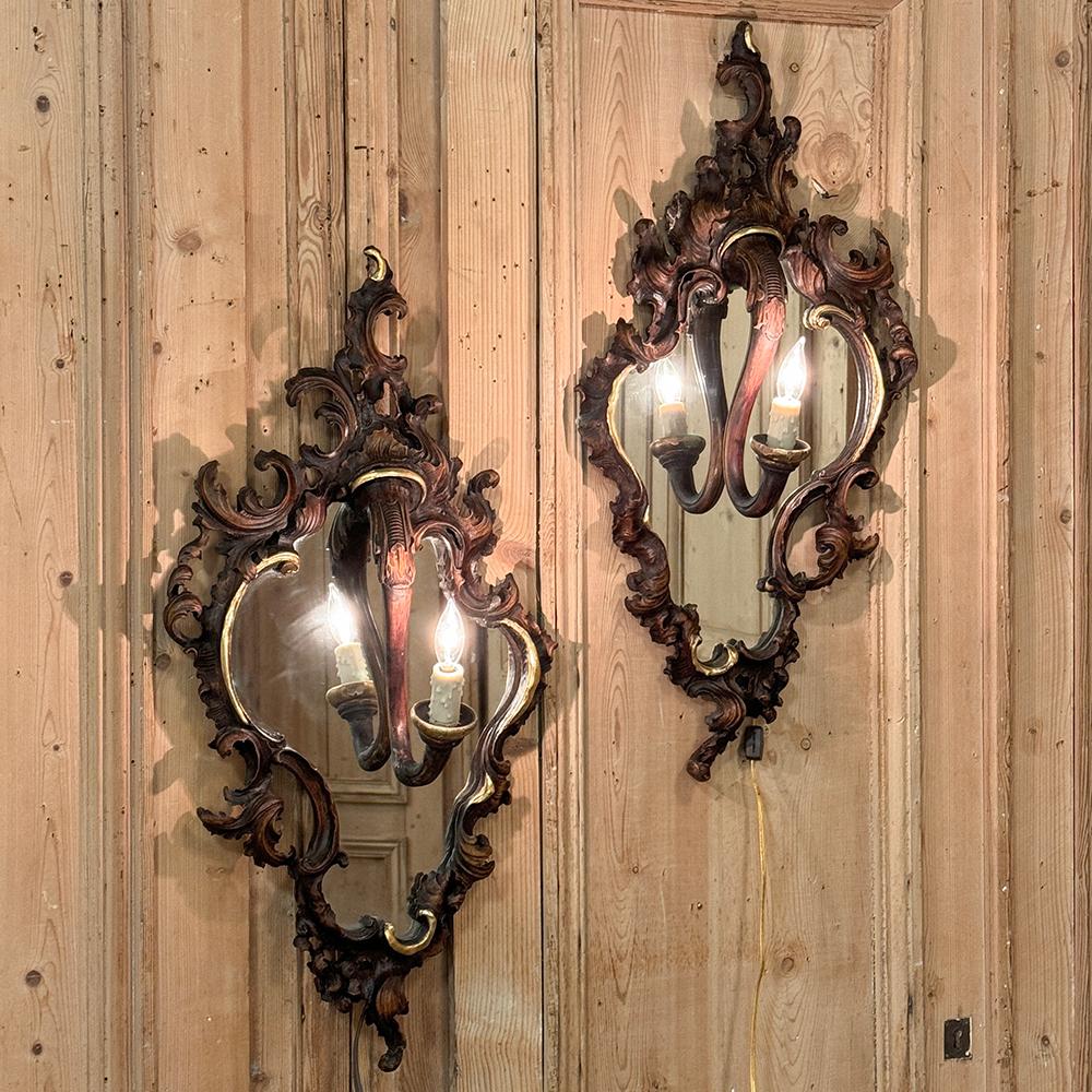 Pair Antique Italian Rococo Hand-Carved Mirrored Wall Sconces will add flair and panache to any room!  Sculpted from solid walnut, each frame exhibits the exuberant presence of the Rococo, with stylized shell and foliate motifs carved on the entire