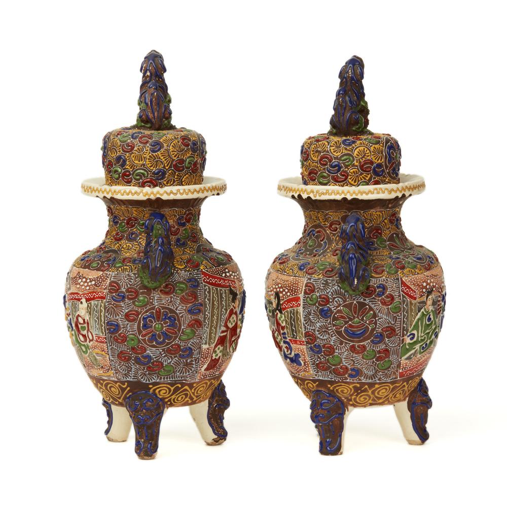 A fine pair antique Japanese Meiji Satsuma Moriage enameled pottery koros and covers with lion dog handles and with a lion dog resting on a ball finial. The koros are of rounded bulbous shape raised on three stylised mask legs the body decorated