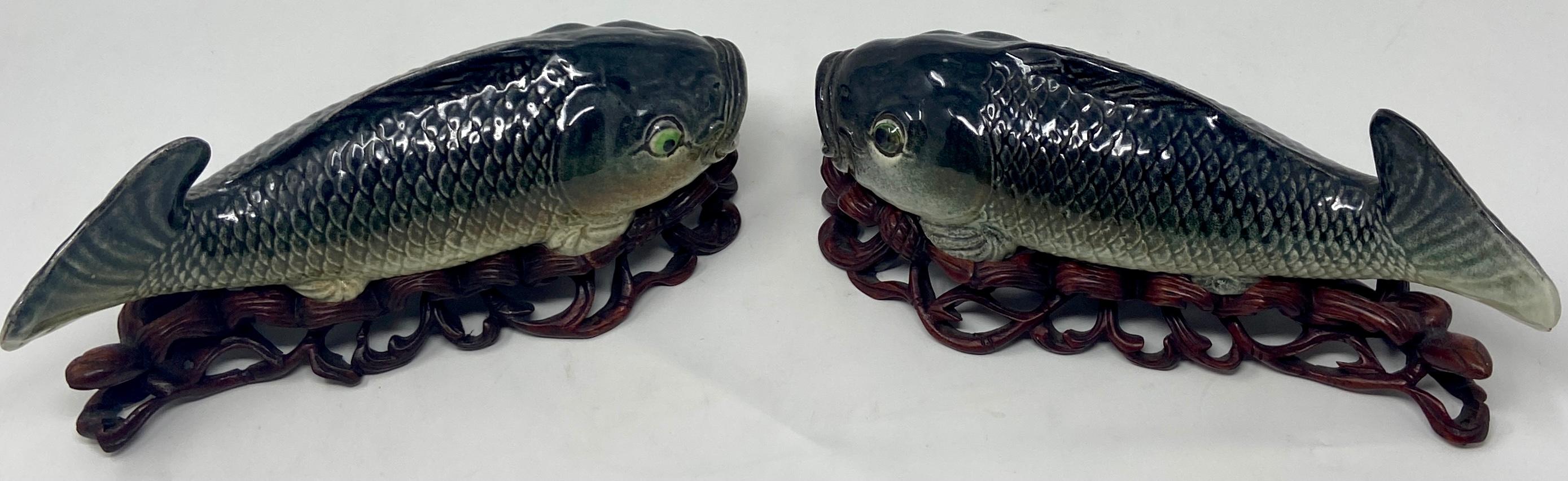 Pair antique late 19th century Chinese porcelain fish figures on carved stands.