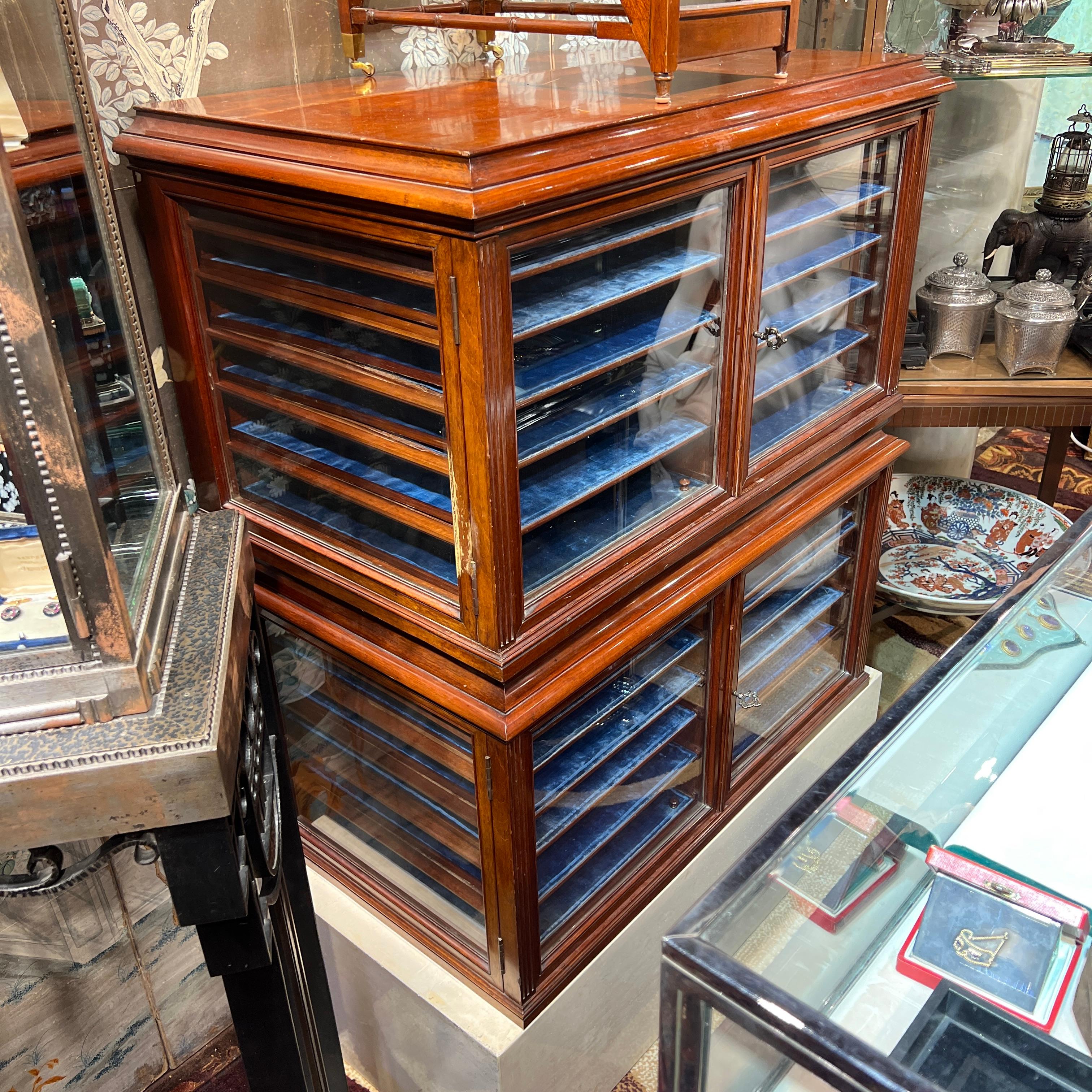 Our pair of antique jewelry display cases were crafted in Germany, circa 1890s, from mahogany with brass hardware, including one original key. They have six removeable trays with turned handles and old (possibly original) blue fabric surfaces. Lock