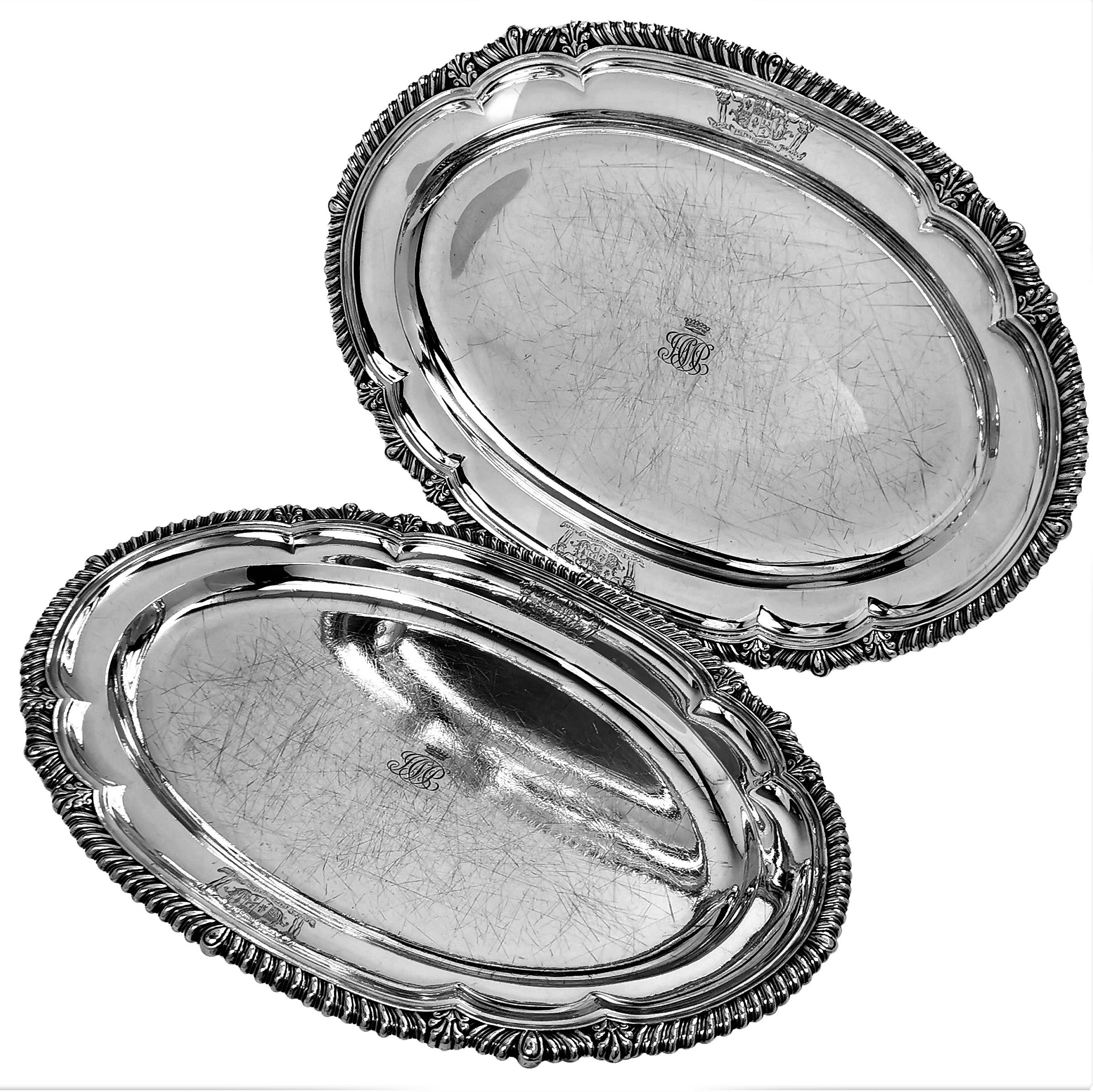 A pair of Antique sterling Silver Meat Platters with a shaped oval form, embellished with a classic gadroon edge. Each Silver Serving Platter has a a pair of Armorials engraved on the rim and a small monogram in the centre topped with the coronet of
