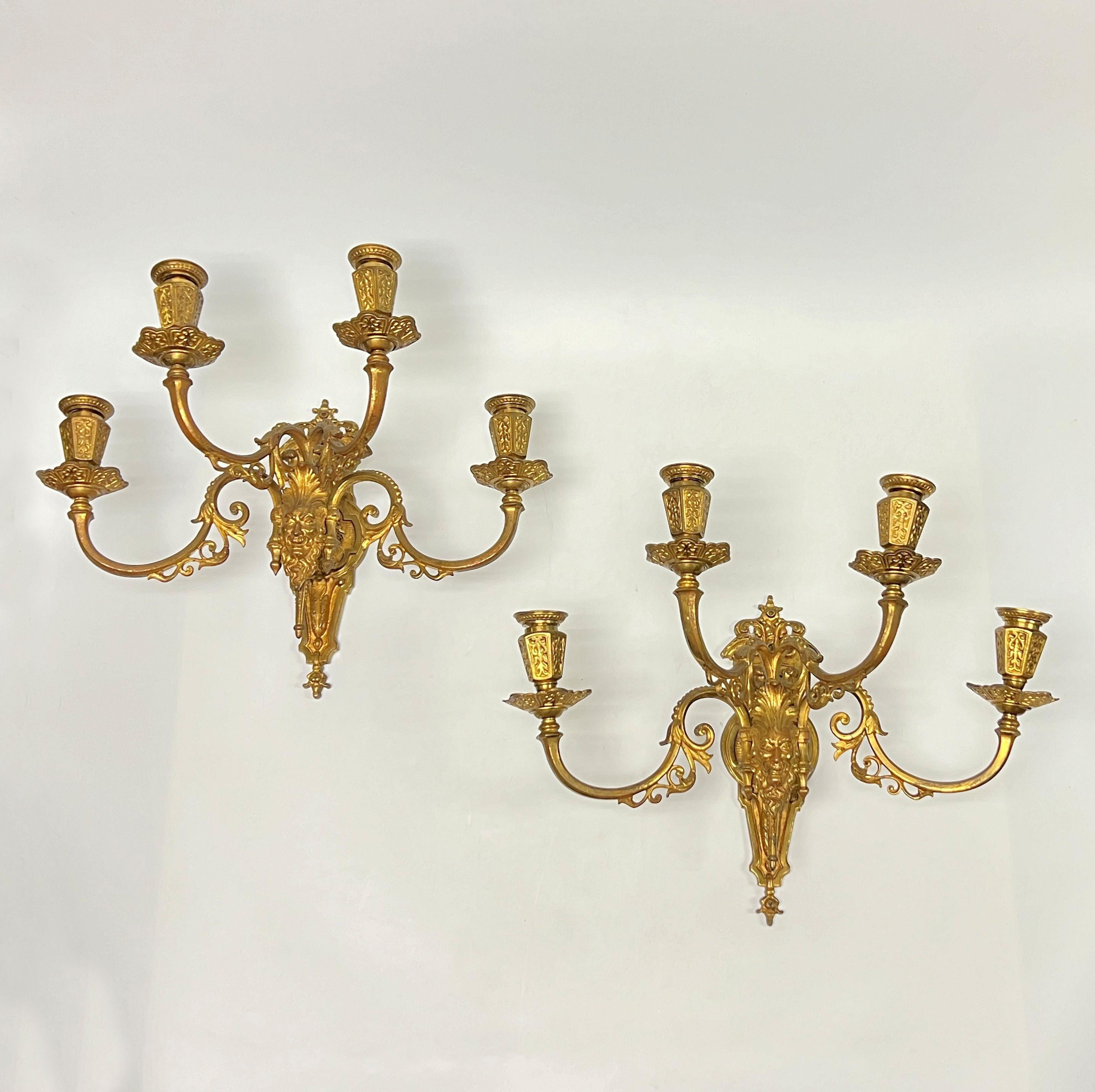 La nostra coppia di grandi applique in bronzo dorato in stile rinascimentale presenta motivi neoclassici, tra cui una maschera prominente alla base e quattro bracci a candela con le loro bobeches originali.  Apparentemente senza segno