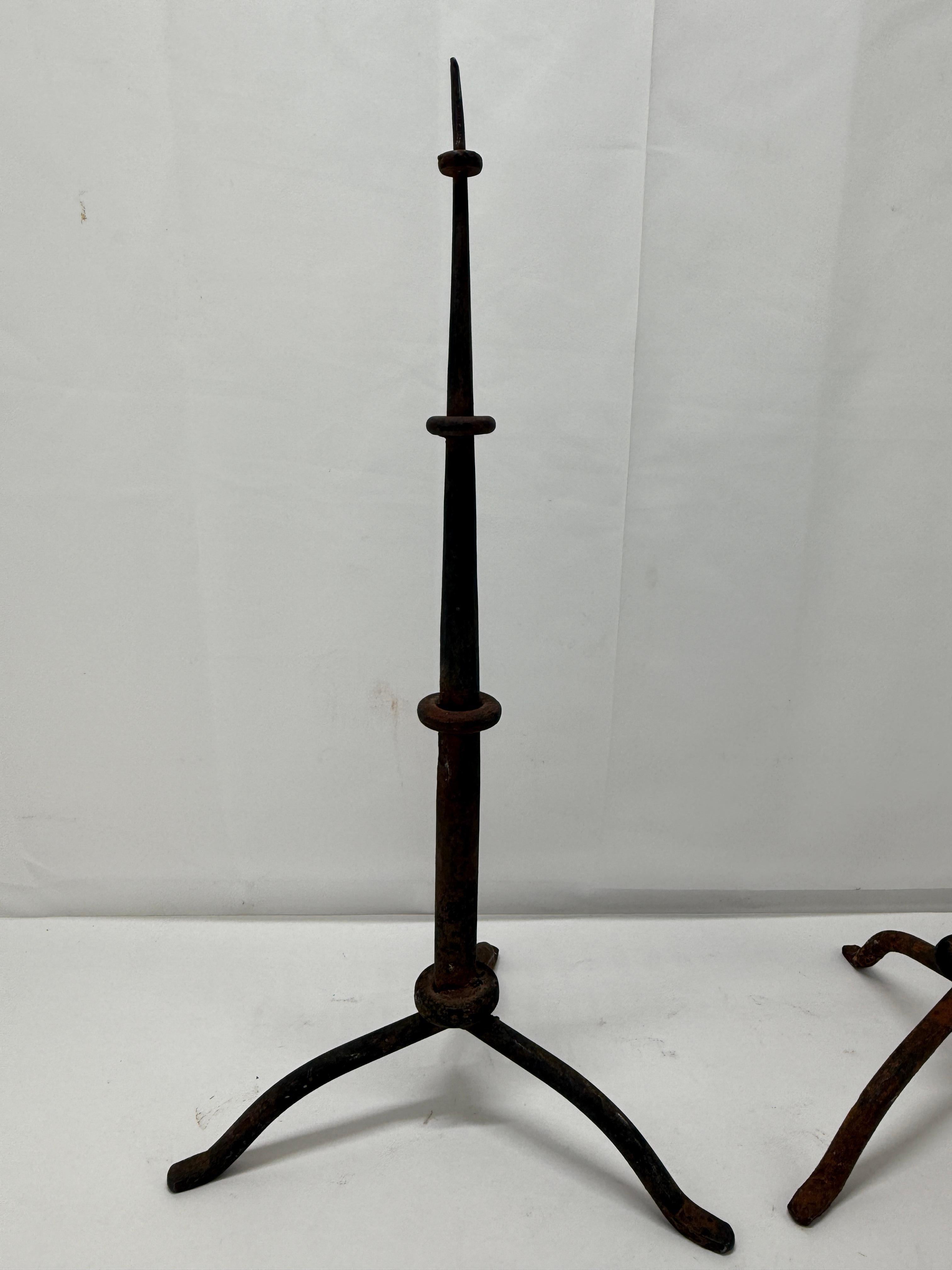 Este par de prickets de hierro de estilo colonial español, de principios del siglo XX o posiblemente del XIX, es un sorprendente ejemplo de artesanía forjada a mano de una época pasada. Elaborados según la tradición de la metalistería colonial