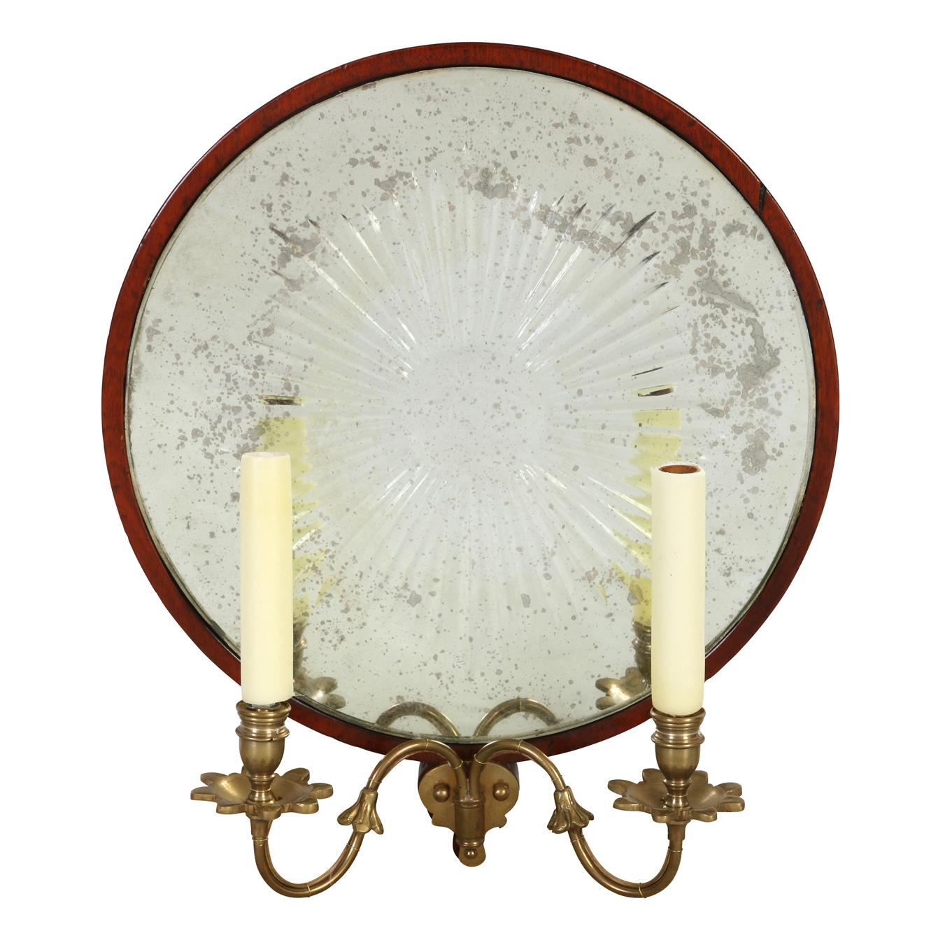A pair of round double arm brass wall sconces with antiqued mirror backs that have a starburst design.
