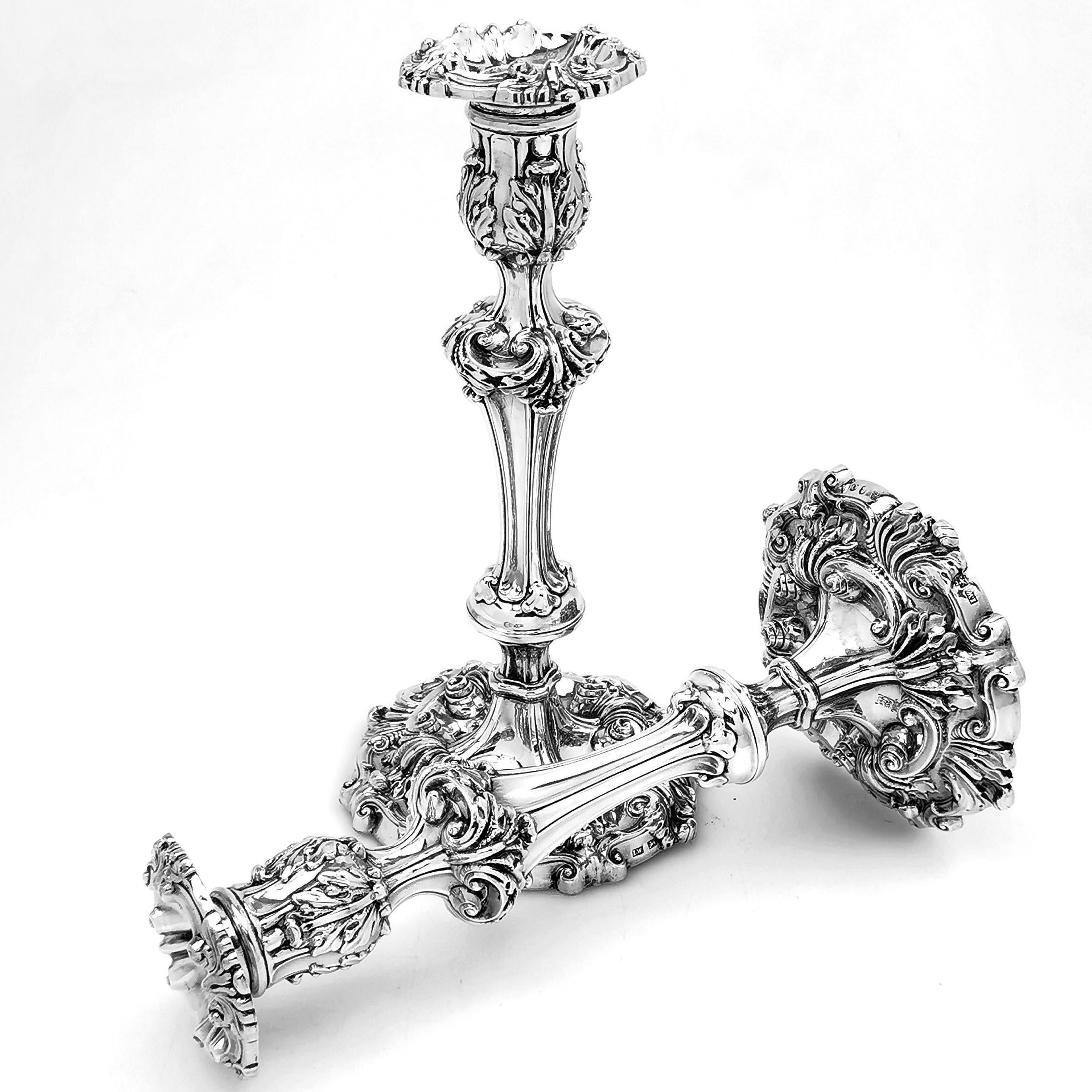 A pair of magnificent antique George III solid silver candlesticks decorate with ornate chased designs on the spread foot, the knopped column, the capital and the removable sconce. Each candlestick and sconce have a small engraved crest.

Made in