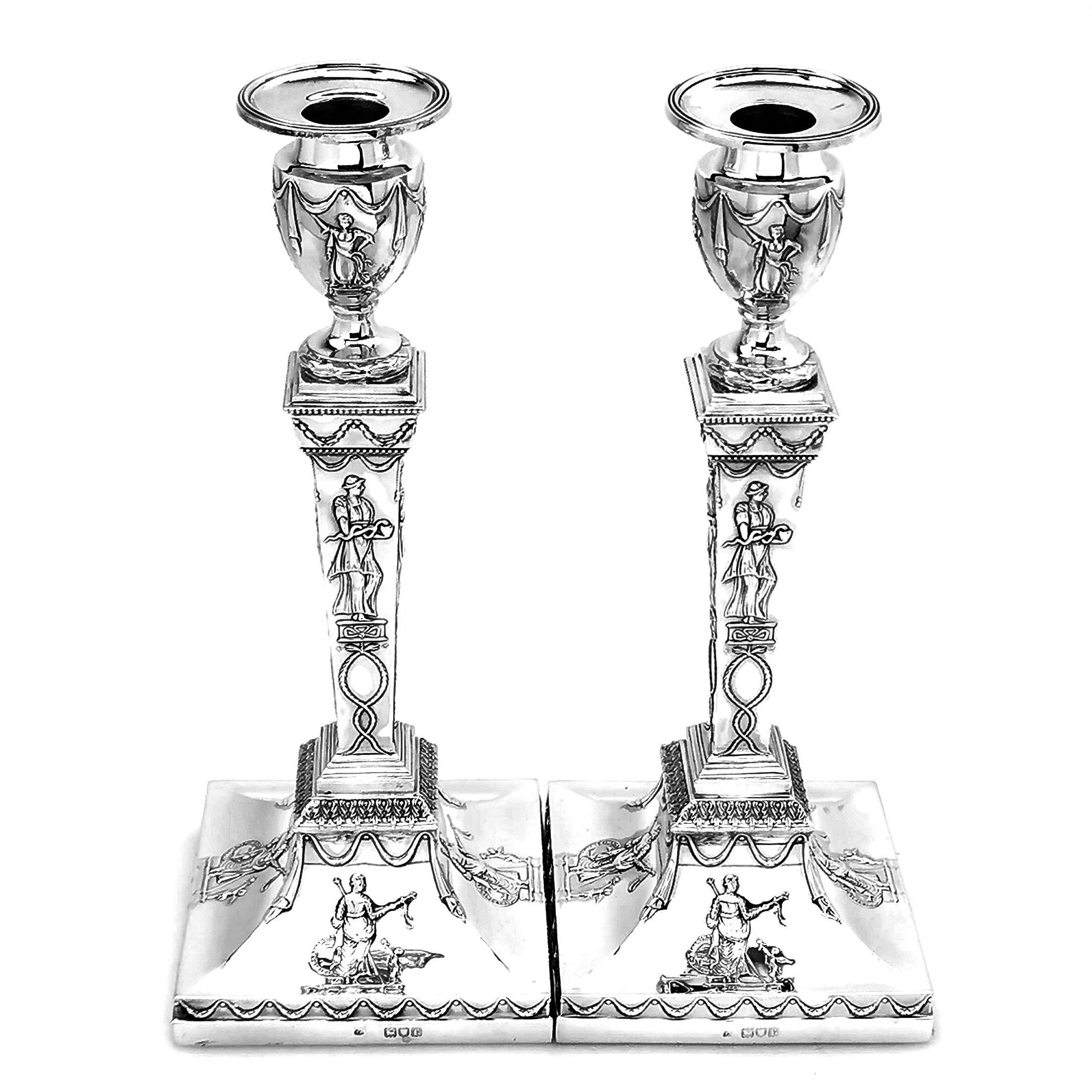 Pair of Antique Silver Candlesticks with square bases and decorated with beautiful chased images of classical figures on the base, columns and capitals. There are further chased patterns featuring fabric and leaf swags.

Made in London in 1901 by