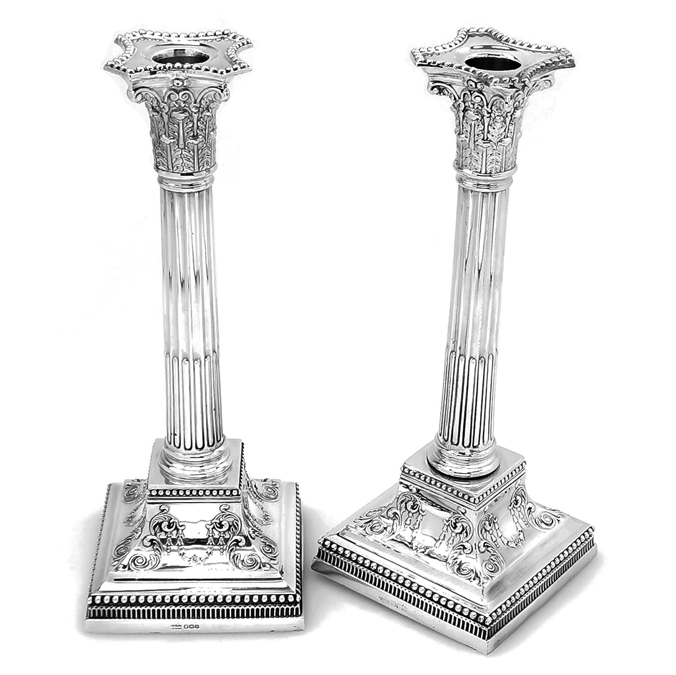 A pair of Antique sterling Silver Candlesticks in a classic Corinthian column design. These Candlesticks have square bases decorated with pretty chased scroll patterning. The border of the square foot and the edging of the removable sconce have a