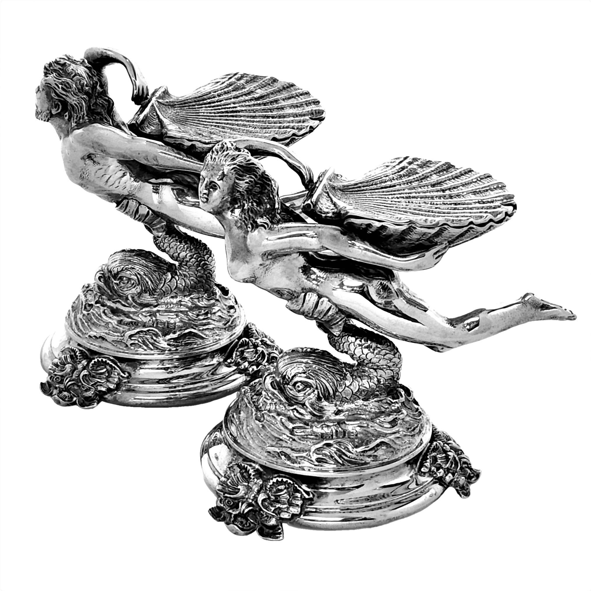 A pair of magnificent Antique solid Silver Salts showing a classical figure supported by a medieval style dolphin on a spread foot. One figure is female and one male and each holds a large lidded shell.

Made in London, England in 1913 by L A