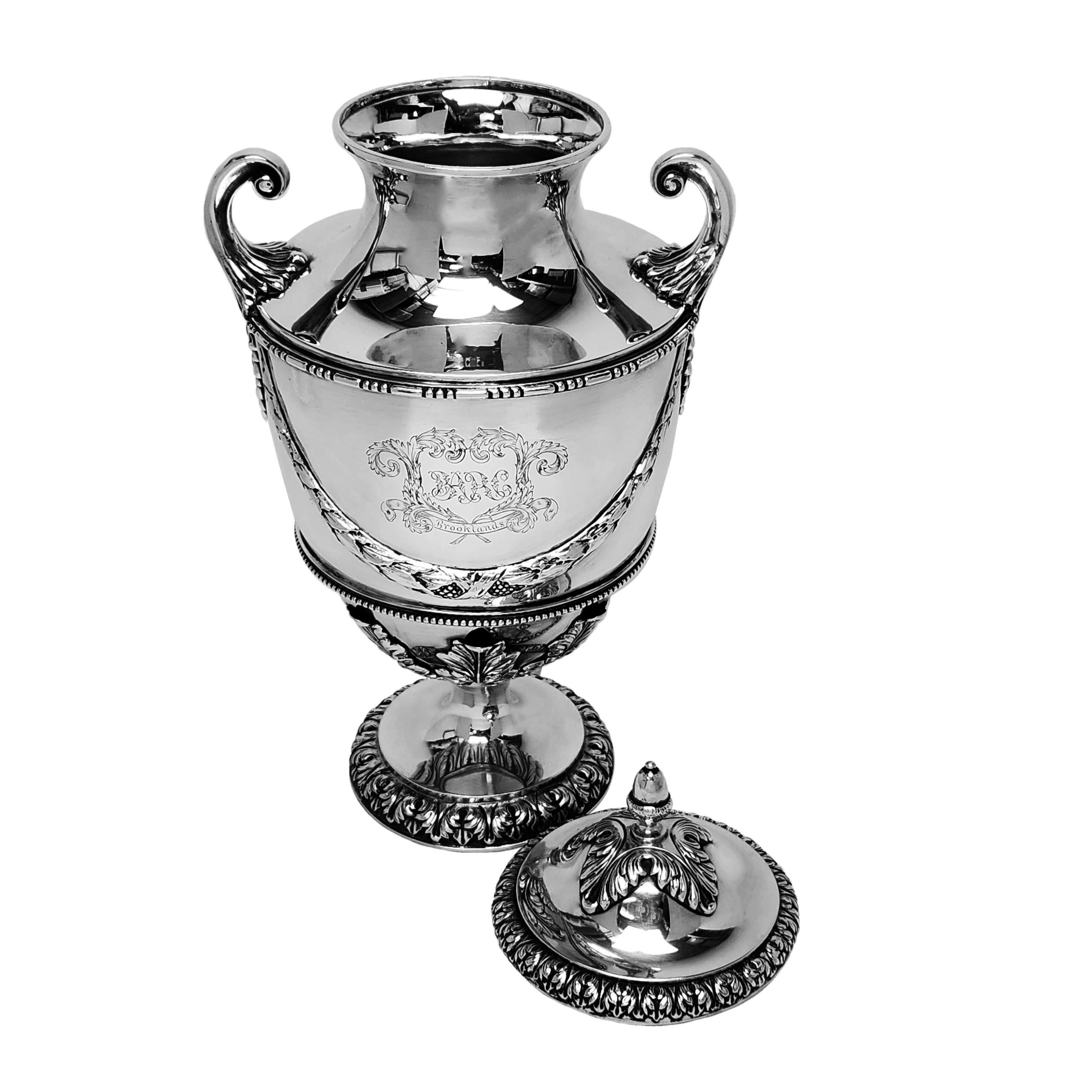 A pair of beautiful Antique solid Silver Lidded Vases in the shape of classical urns. The body of each Silver Vase is decorated with traditional foliate swags  and each has a large armorial engraved on the one side. The upper rim and foot are