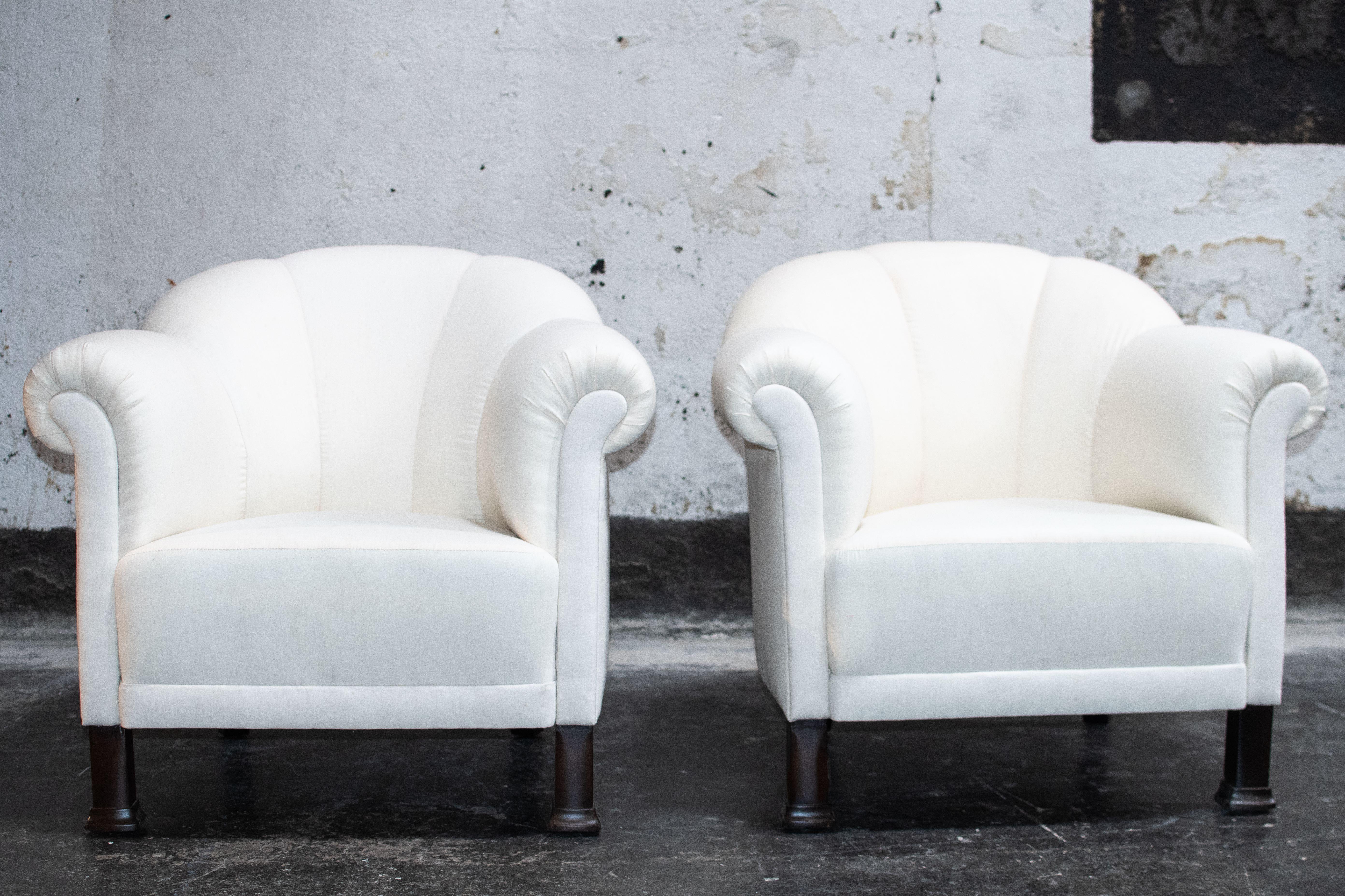Pair of Swedish Art Deco club chairs. Featuring traditional Art Deco elements such as a deep seat, a channeled barrel back, and rolled arms. Restored by our team of craftsmen while maintaining the vintage integrity of the piece. They have been