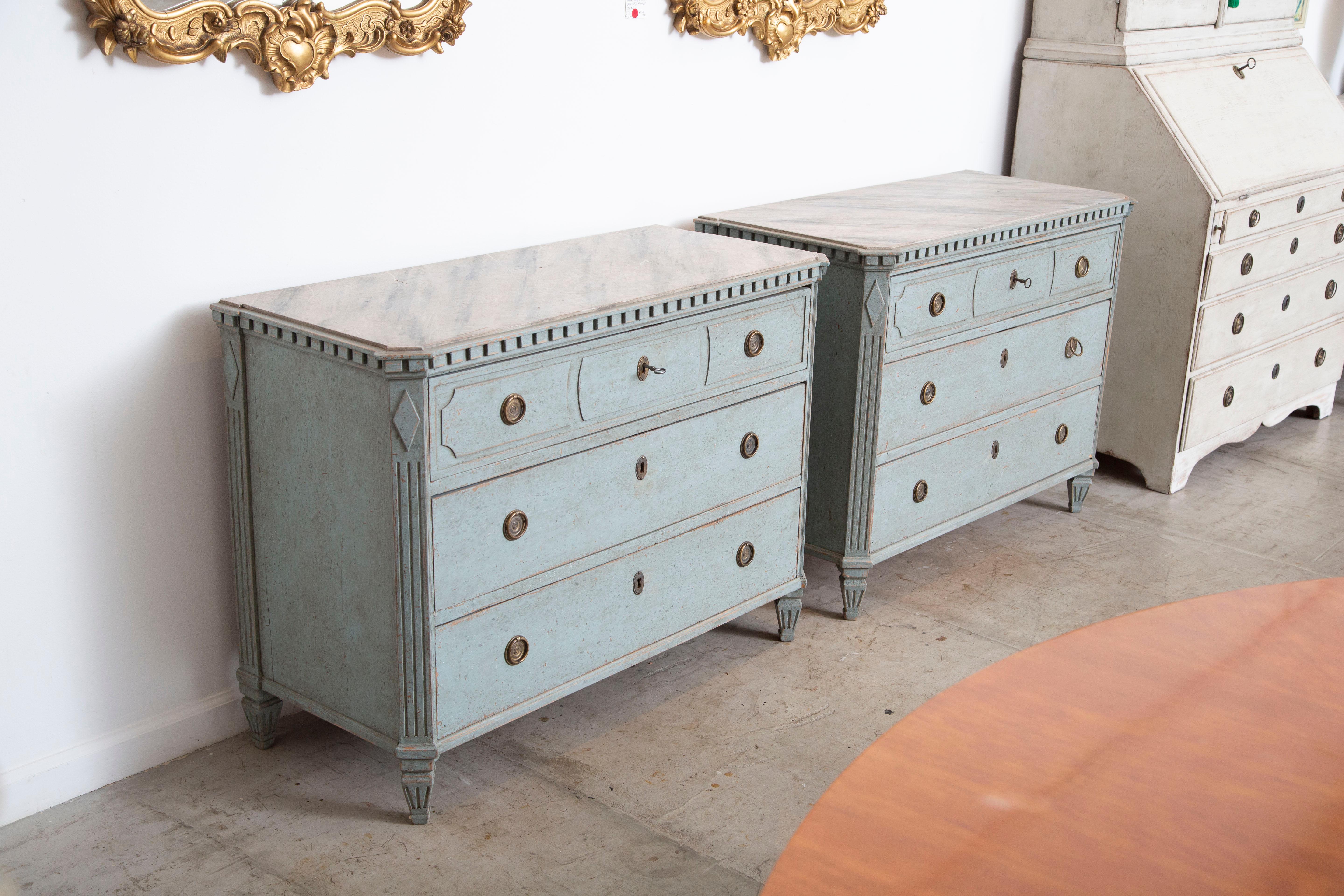 Pair Antique Swedish Gustavian style blue distressed painted chests. Tops are faux painted in greyish marble and below is a nicely caved dental moulding. Cut corners with fluted details and oval carved rosettes, tapered fluted legs. Three large