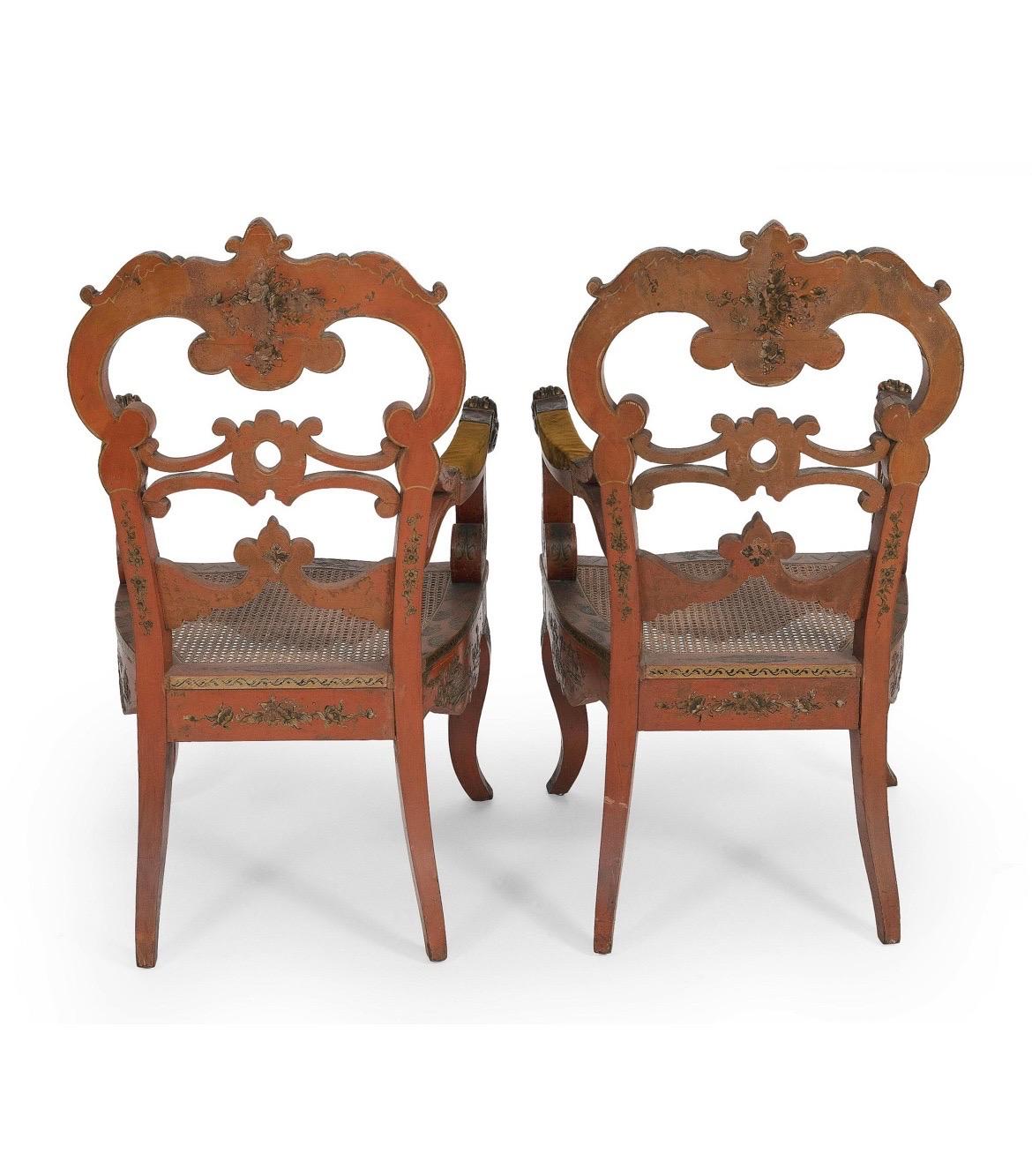 Venetian, Early 20th century. 

An exceptional pair of antique Venetian armchairs with a red lacquer ground and heavily painted gold gilt chinoiserie decoration across surfaces. Each chair features figural warriors, pagoda cities and traditional