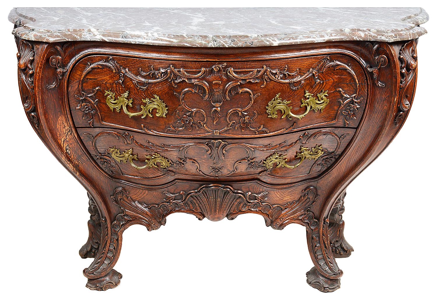 An impressive pair of Venetian style bombe commodes, having their original marble tops, each having carved Rococo style decoration, two drawers with stylised brass handles, raised on out swept legs with shell and leaf decoration.