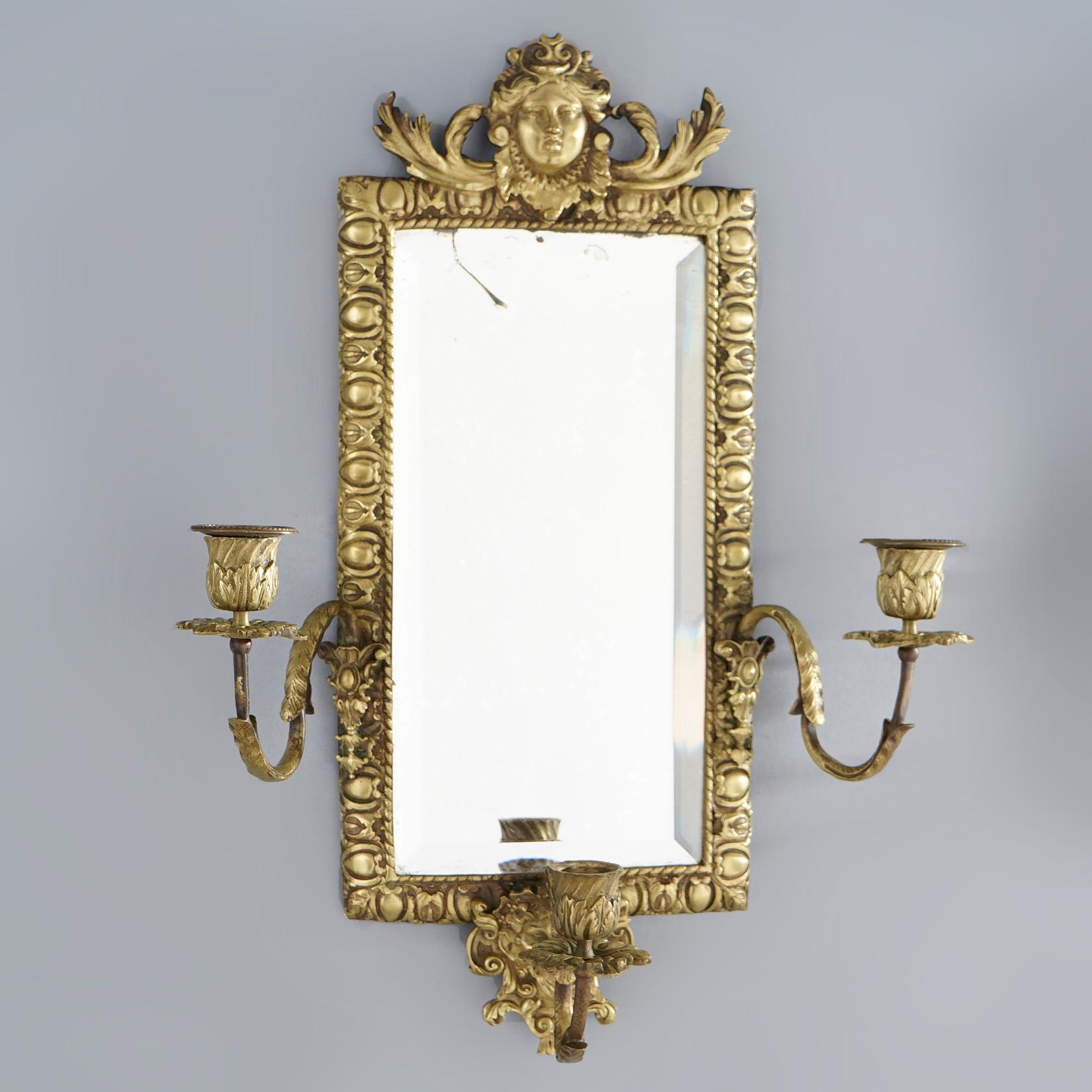 A matching pair of antique Victorian wall sconces offer gilt cast metal frames with female mask at crest surmounting beveled mirrors and three scroll form arms terminating in candle sockets, foliate elements throughout, 19th century

Measures-