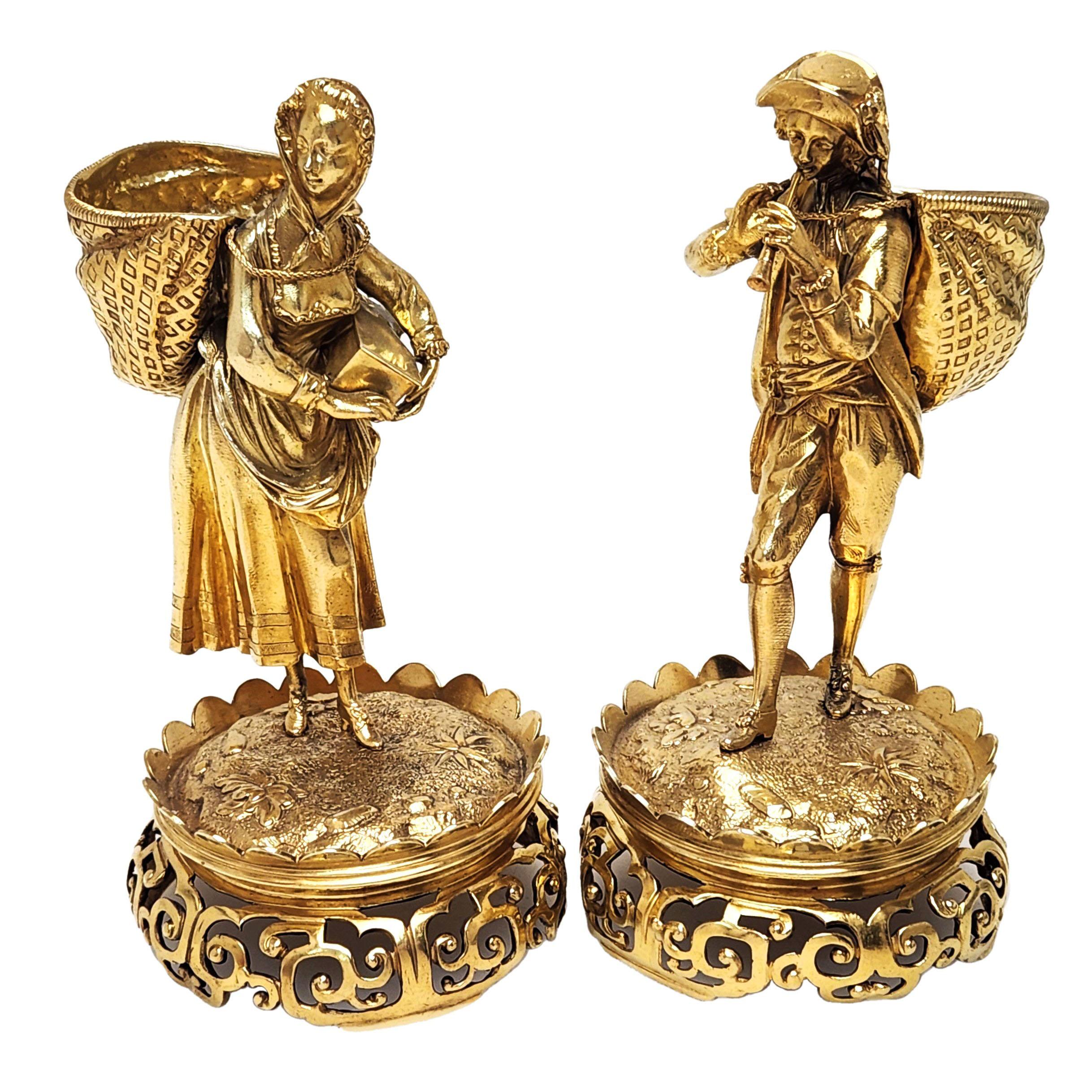 A pair of magnificent Antique Victorian Figural Salts known as Boy Girl Salts. This pair of Silver Salts is fashioned in the shape of a male and a female figure as peasants. The Girl has a Basket on her back and a Box in her arms. The Boy us wearing