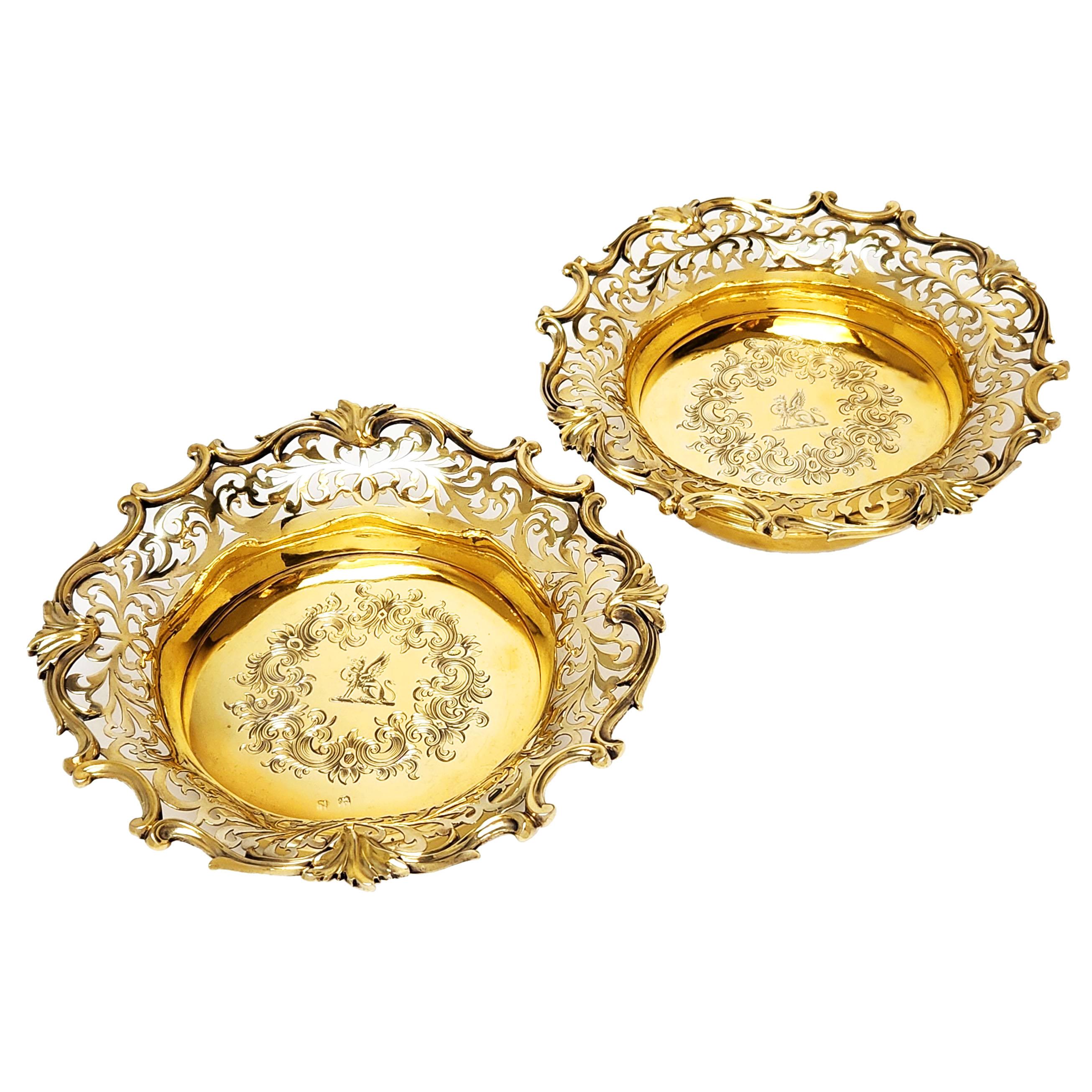 A pair of beautiful Antique Solid Silver Wine Bottle Coasters with an elegant gilded finish. The coasters have and ornate pierced design on the sides and a leaf and scroll boarder on the rim. The gilded silver base of each of the Wine Coasters are