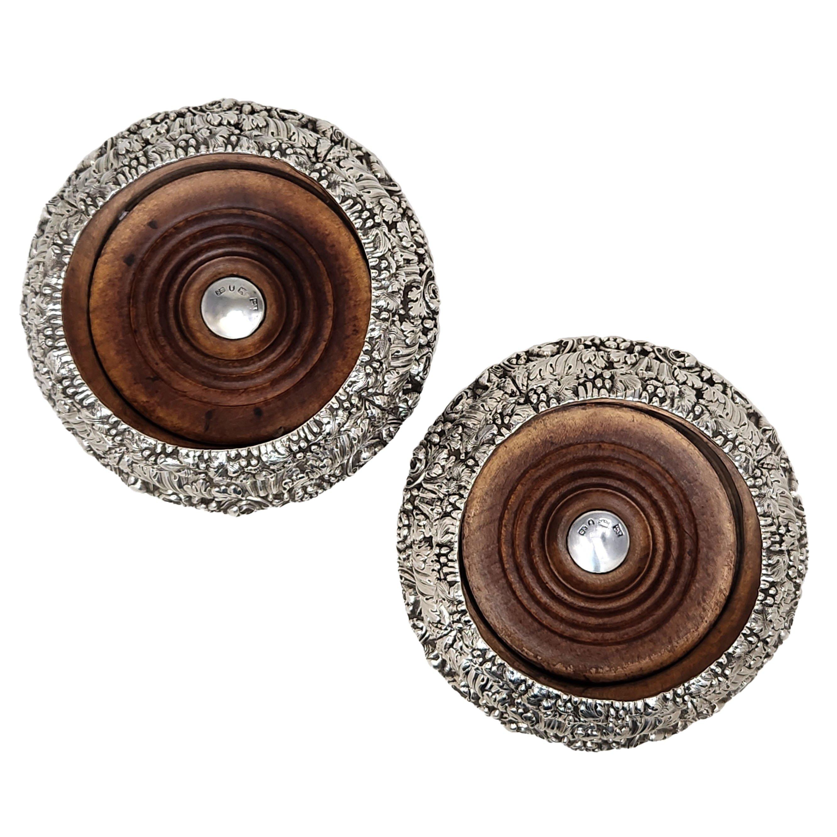 A pair of magnificent and unusual Antique William IV Sterling Silver Wine Bottle Coasters with a stepped chased floral and foliate design on the exterior of the coasters. The base of coasters is made of turned wood and each coaster has a large