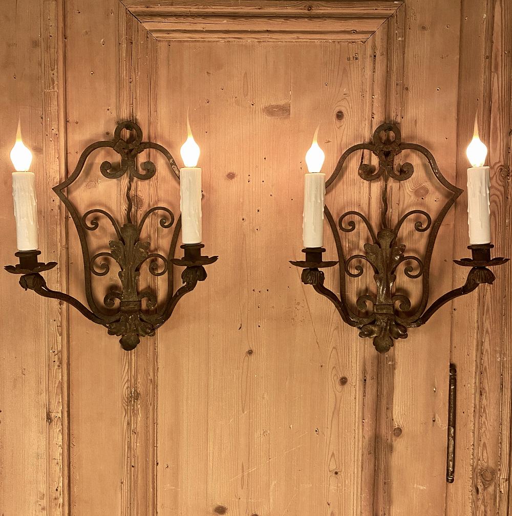 Pair of antique wrought iron wall sconces, electrified! A great choice for adding both the ambiance of antique lighting and the flair of Country French styling, this pair of solid forged iron sconces were originally intended for candles, but have