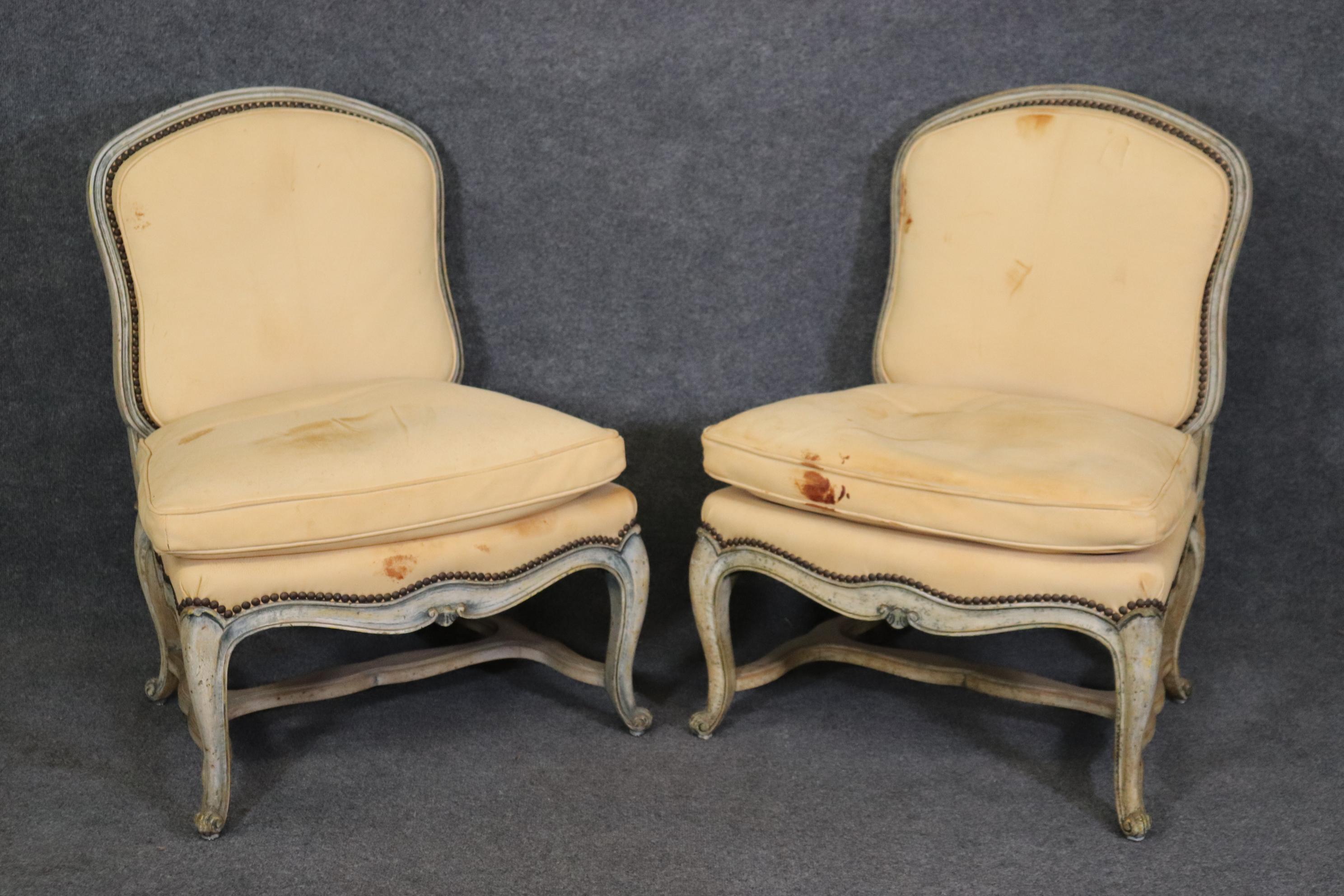 This is a gorgeous pair of genuine leather armless boudoir or bergere chairs. The chairs look antique but were made during the 1980s era. They are in their original stained and in one area, torn leather upholstery. The upholstery can be