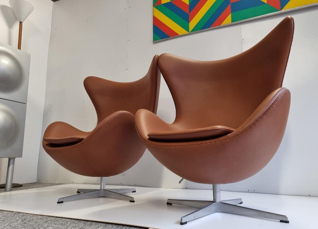 Amusante paire de chaises Arne Jacobsen Egg en cuir qonjac, conçues dans les années 50 et fabriquées par Fritz Hansen. De véritables icônes. Cette paire date de 2007 et est en superbe état. Elle a été récemment restaurée par un expert avec ce cuir