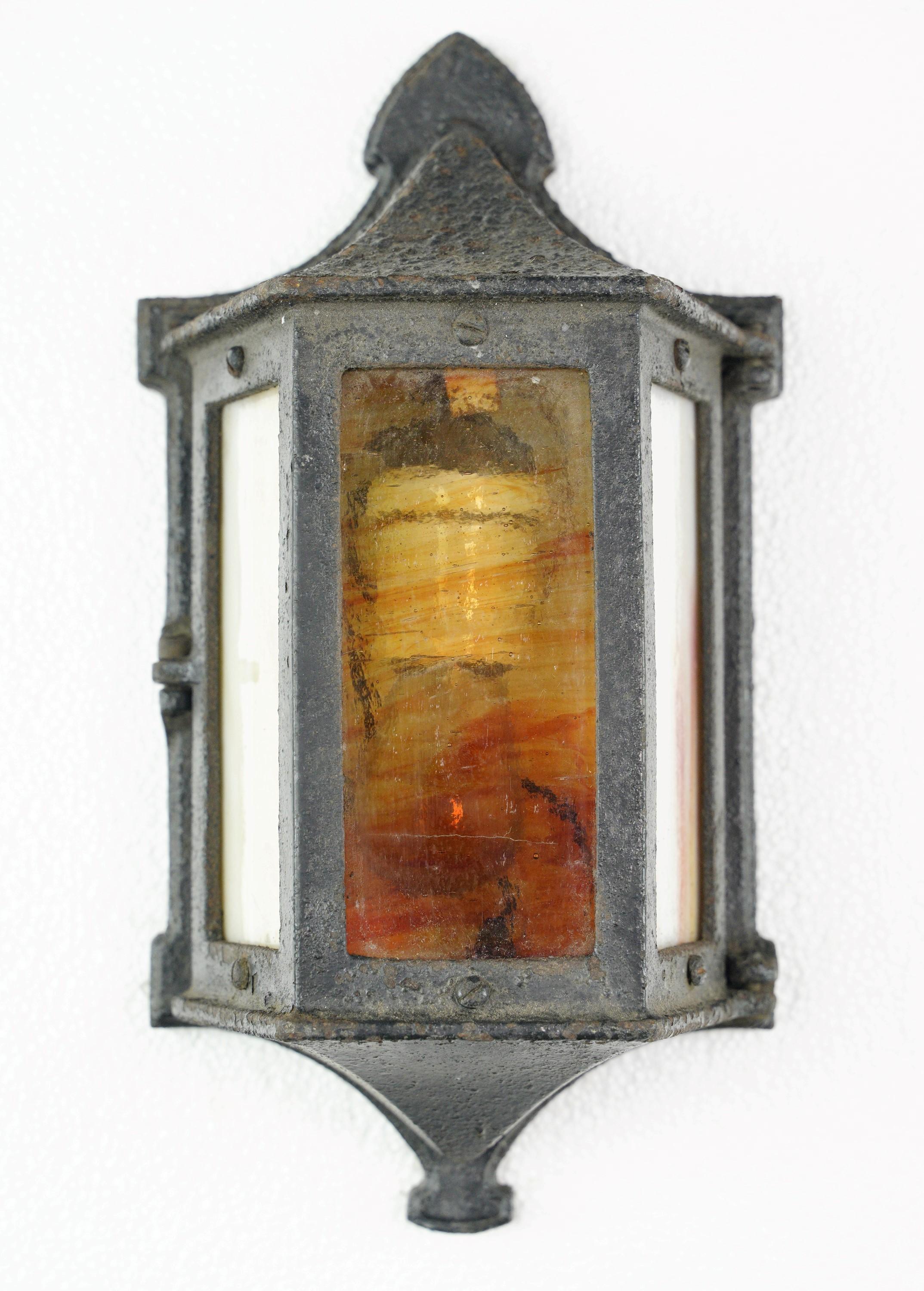 This pair of Art & Crafts cast iron and stained glass outdoor wall sconces beautifully blend artistic craftsmanship with functional outdoor lighting. They are in good condition and require one single standard medium base lightbulb. Cleaned and