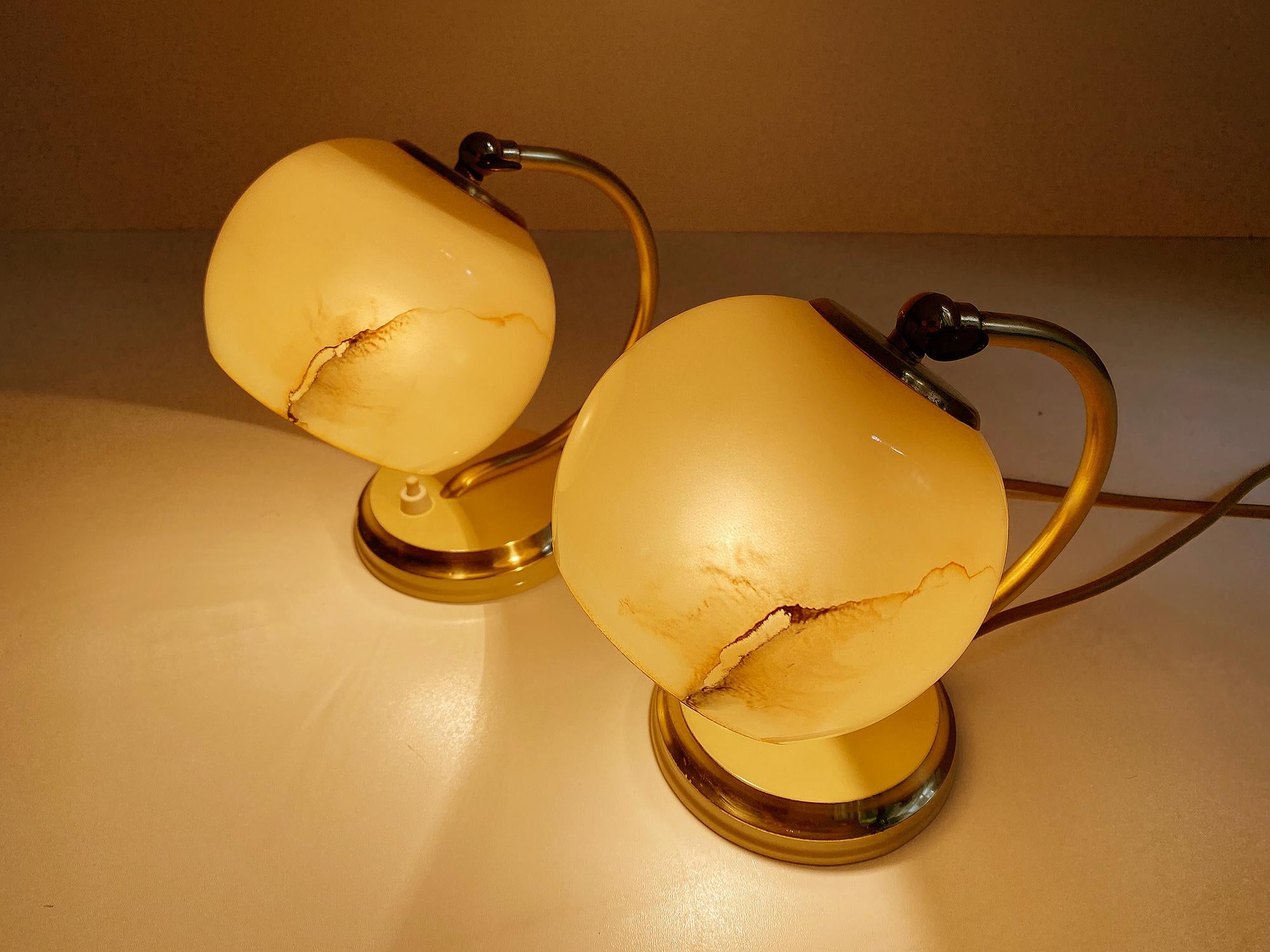 Gorgeous pair of Art Deco table lamps, featuring a cream white enameled base with brass trim, polished brass cradle shaped stems and caps with cream white trim, absolutely stunning marbleized opaline glass shades, overlay glass, cream white with
