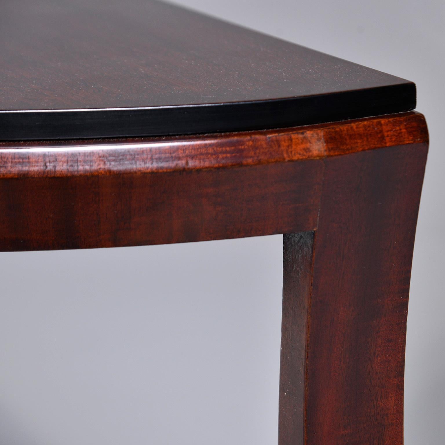 Pair circa 1930s French Art Deco demi lune console tables feature a pedestal base with three curved legs and ebonised details. Unknown maker. Sold and priced as a pair.