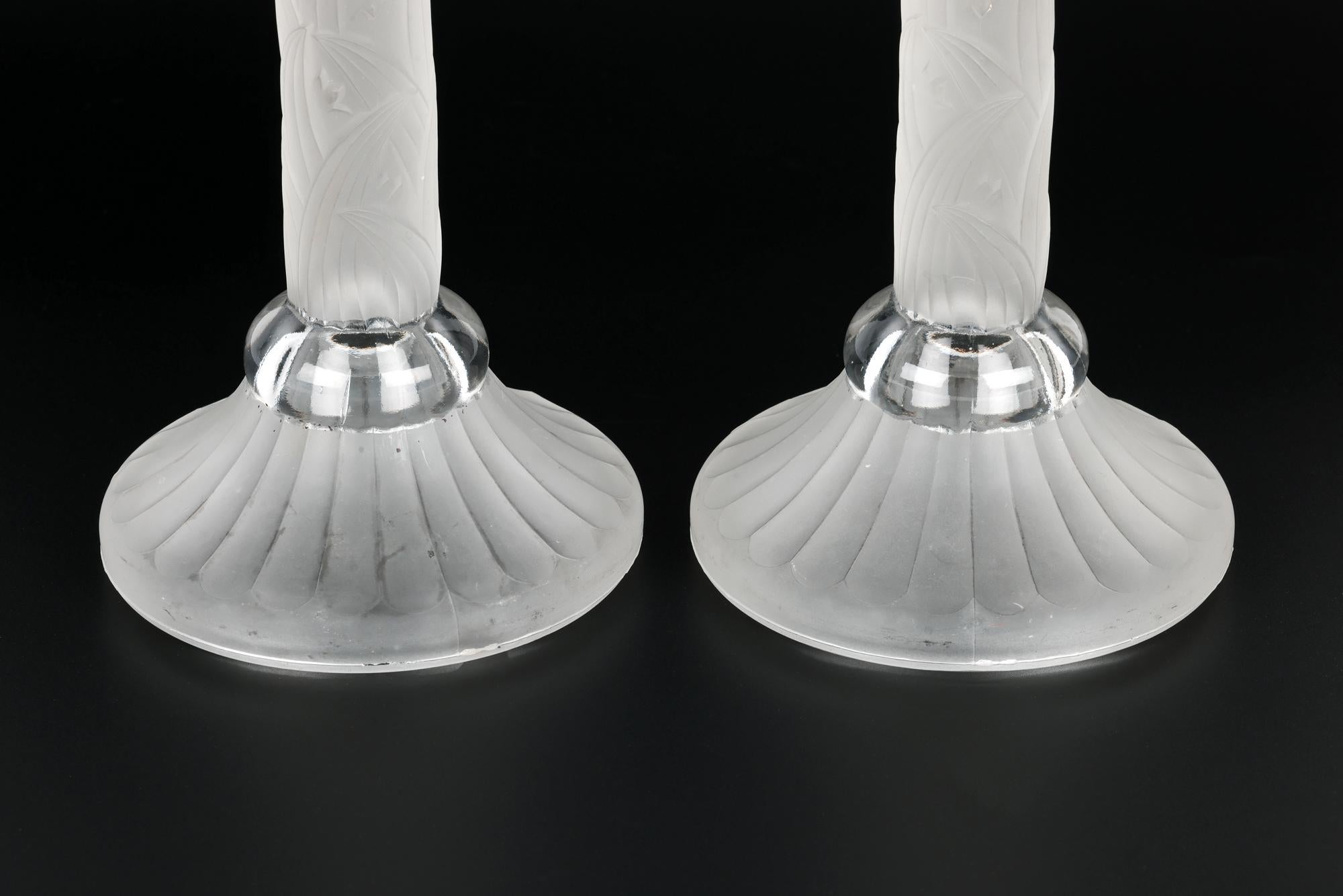 Un'elegante coppia di candelabri in vetro a forma di colonna in stile Art Déco con motivi e smerigliature risalenti al 1930 circa. I candelieri modellati poggiano su una base rotonda rialzata e zoccolata con alti e stretti steli a colonna e con un