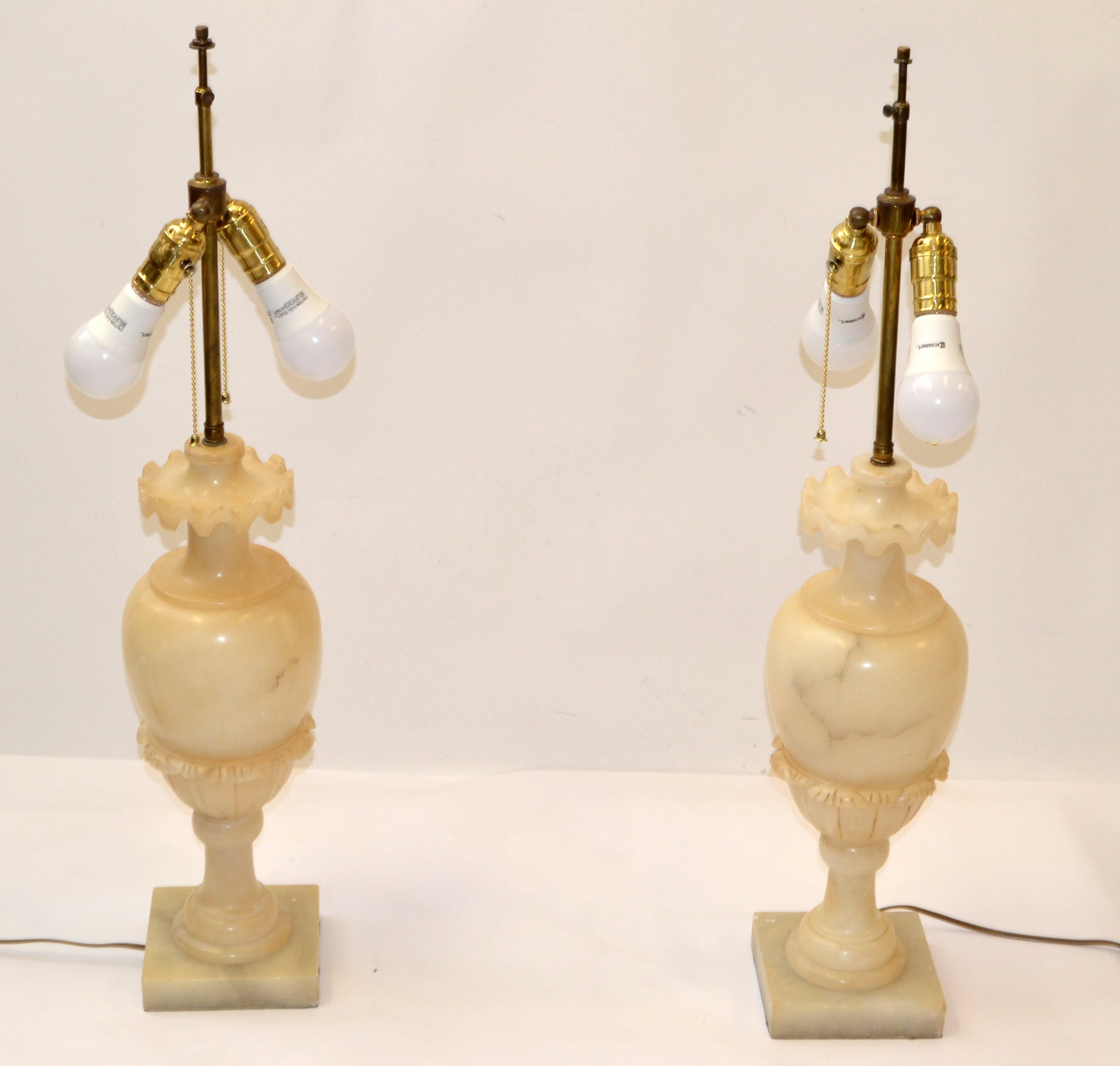 A pair of Urn shaped table lamps in beige color Alabaster with light brown veins. 
All Art Deco Period, hand carved, US rewiring and made in Italy circa 1930-1940s. 
The lamp holders are made out of brass with 2 inches expandable Shade Holder,