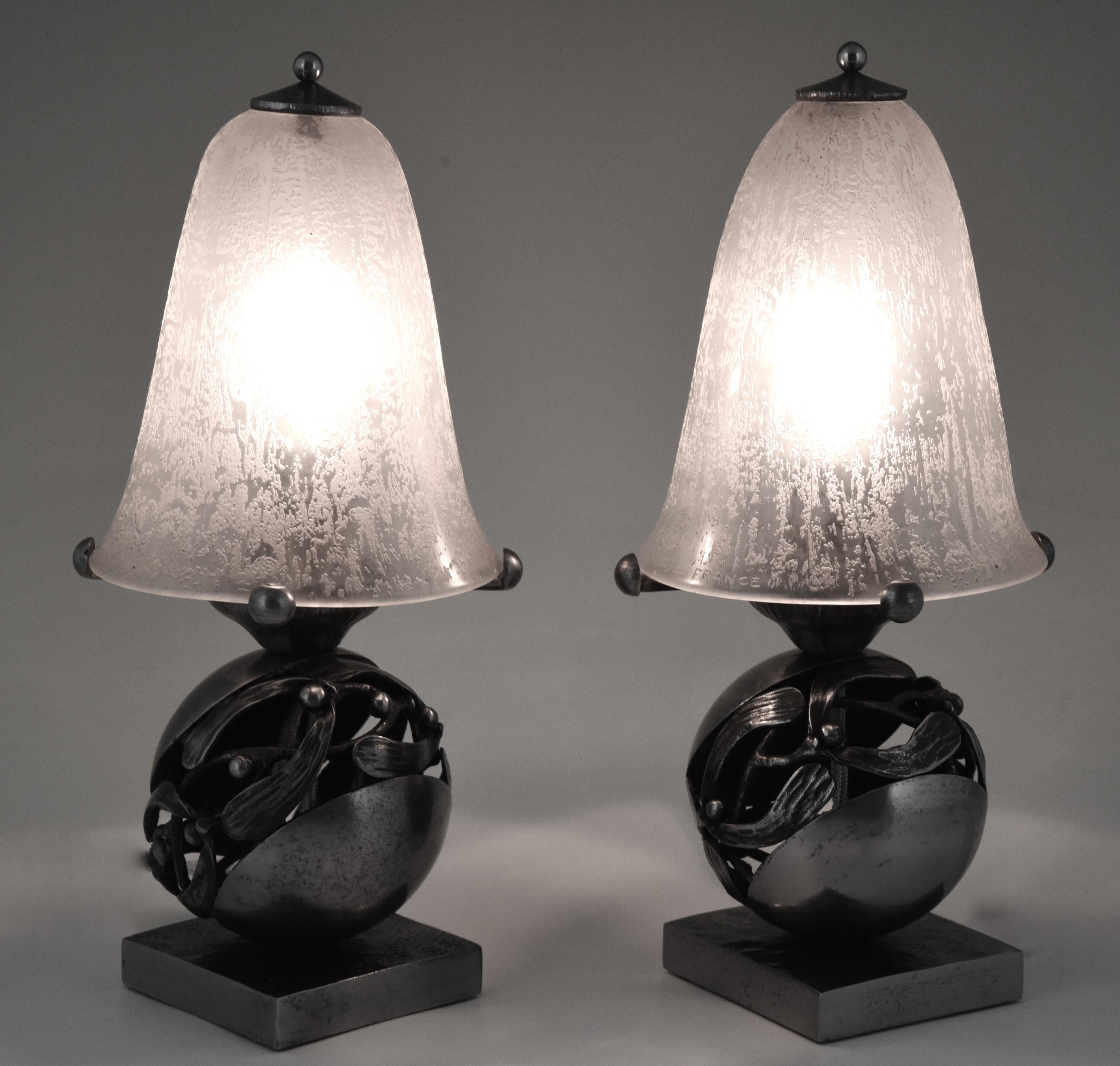 A pair of Edgar Brandt & Daum Mistletoe or “Boule de Gui” Art Deco table lamps. Fine wrought iron base with original silver grey patina. Etched Daum Nancy glass shades, circa 1920.
The Boule de gui is a 