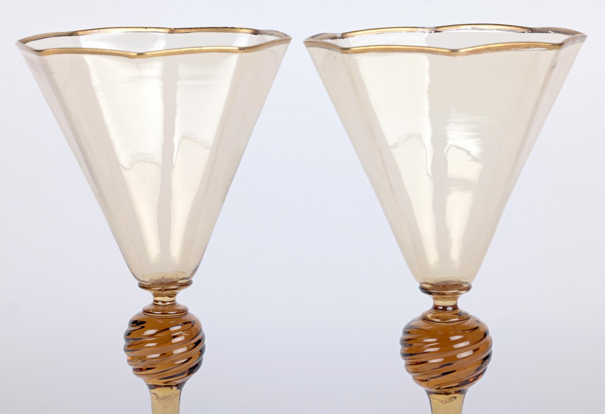 Ein sehr schönes Paar Murano MVM Cappellin bernsteinfarbene Weingläser aus der Zeit um 1925. Die Gläser haben achteckige Schalen mit vergoldetem Rand, die auf großen, gebogenen Stielen und runden Füßen mit vergoldetem Rand stehen. Die Gläser sind