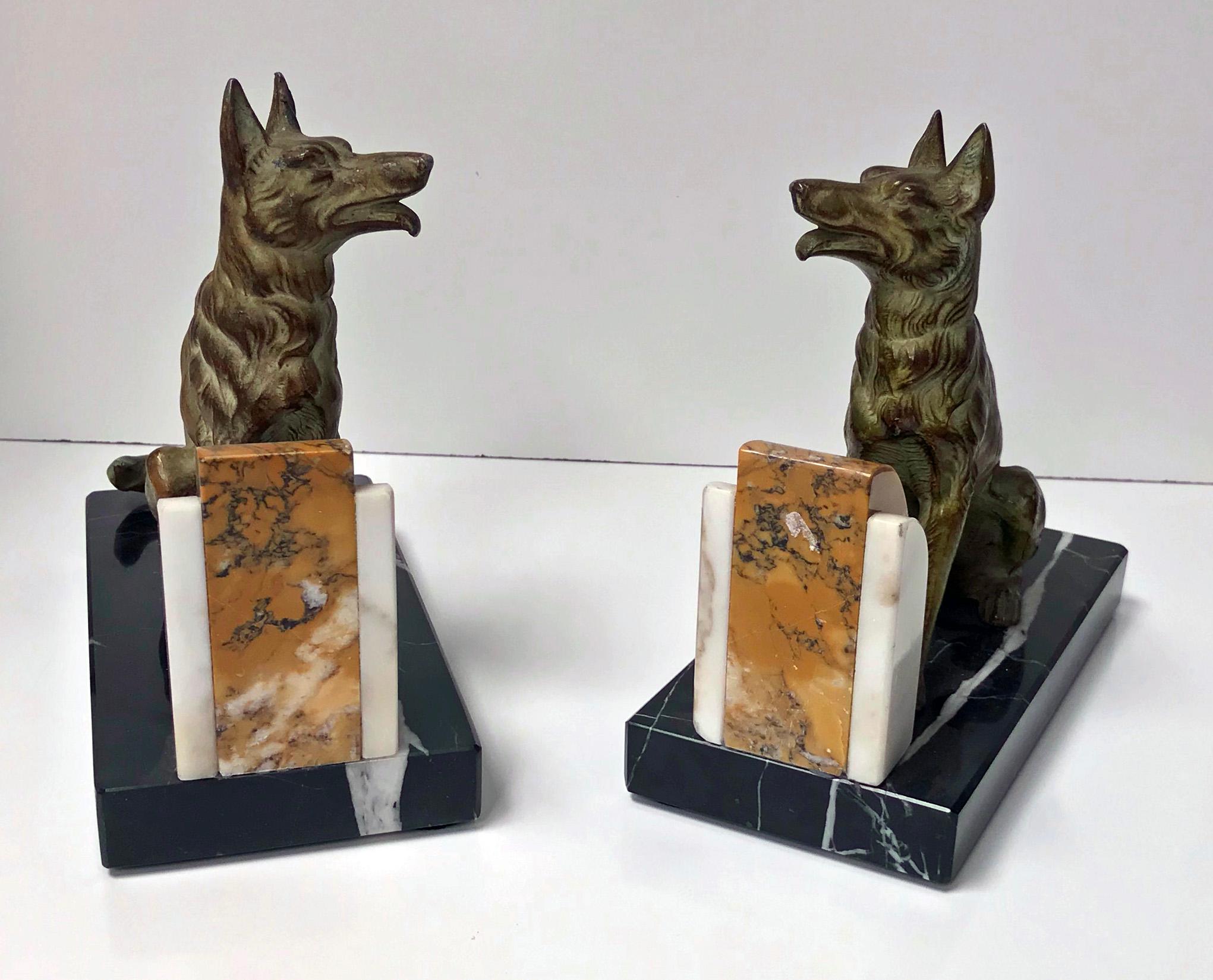 Pair of Art Deco patinated bronze dog bookends, France, circa 1930. Each depicting an Alsatian Dog on black and white marble base. The standing Alsatian of realistic model form, textured body; seated in front of mottled light brown and cream hemi