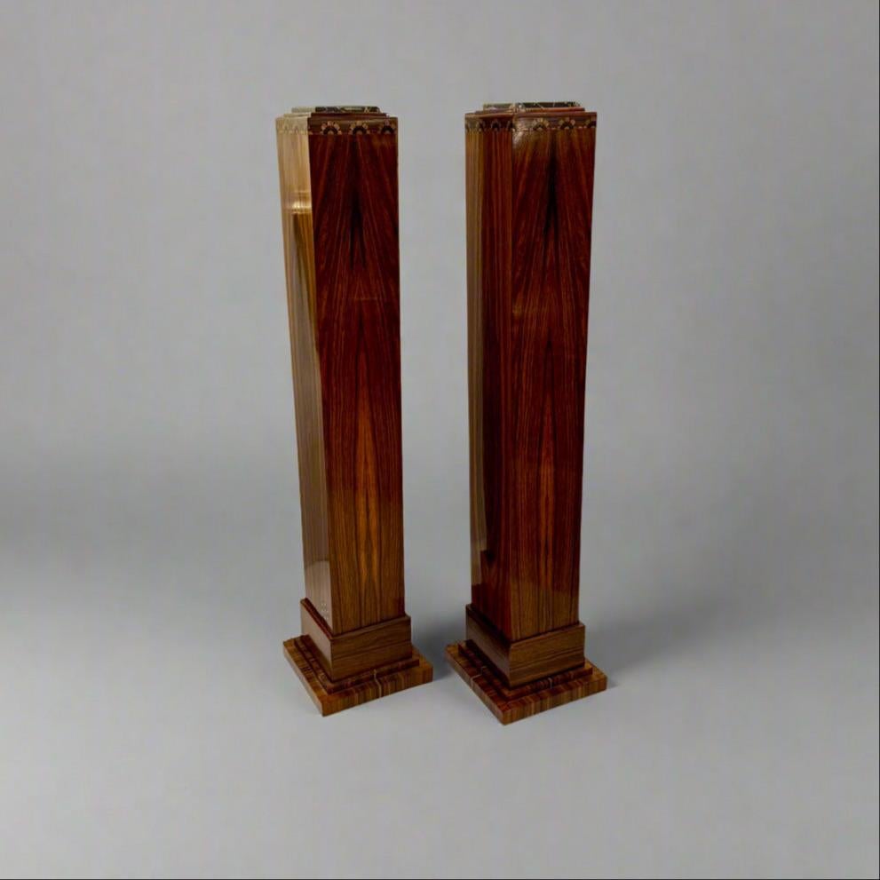Ein Paar Sockelsäulen aus der Zeit des Art déco. Jede quadratische Säule ist aus exotischem Holz gefertigt und mit Intarsien aus Obstholz und Ebenholz verziert und steht auf einem Sockel. Bitte beachten Sie die spezielle Portoro-Marmorplatte auf