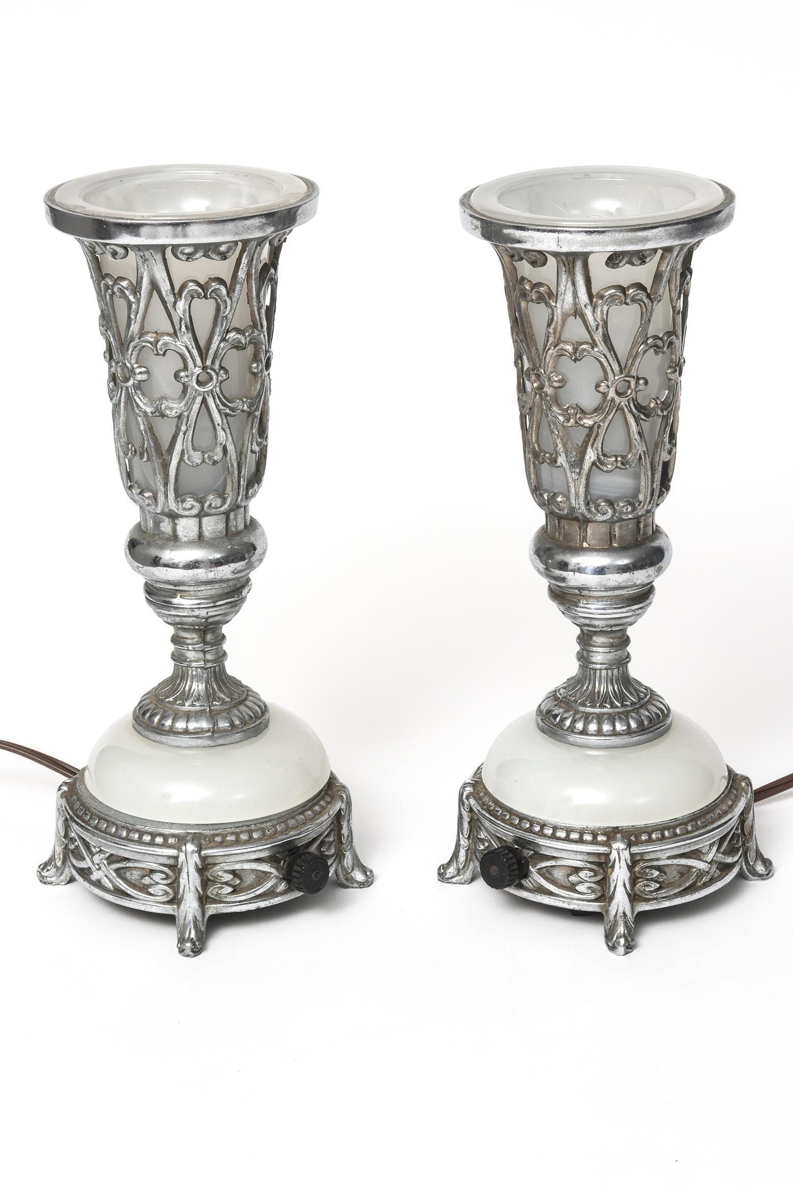 Rare pair of Art Deco table or mantle lamps - perfect for dim romantic lighting or as night lights.
These lamps are made of chrome plated metal and milk glass. The top section over the white tulip shaped glass section is pierced. The center section