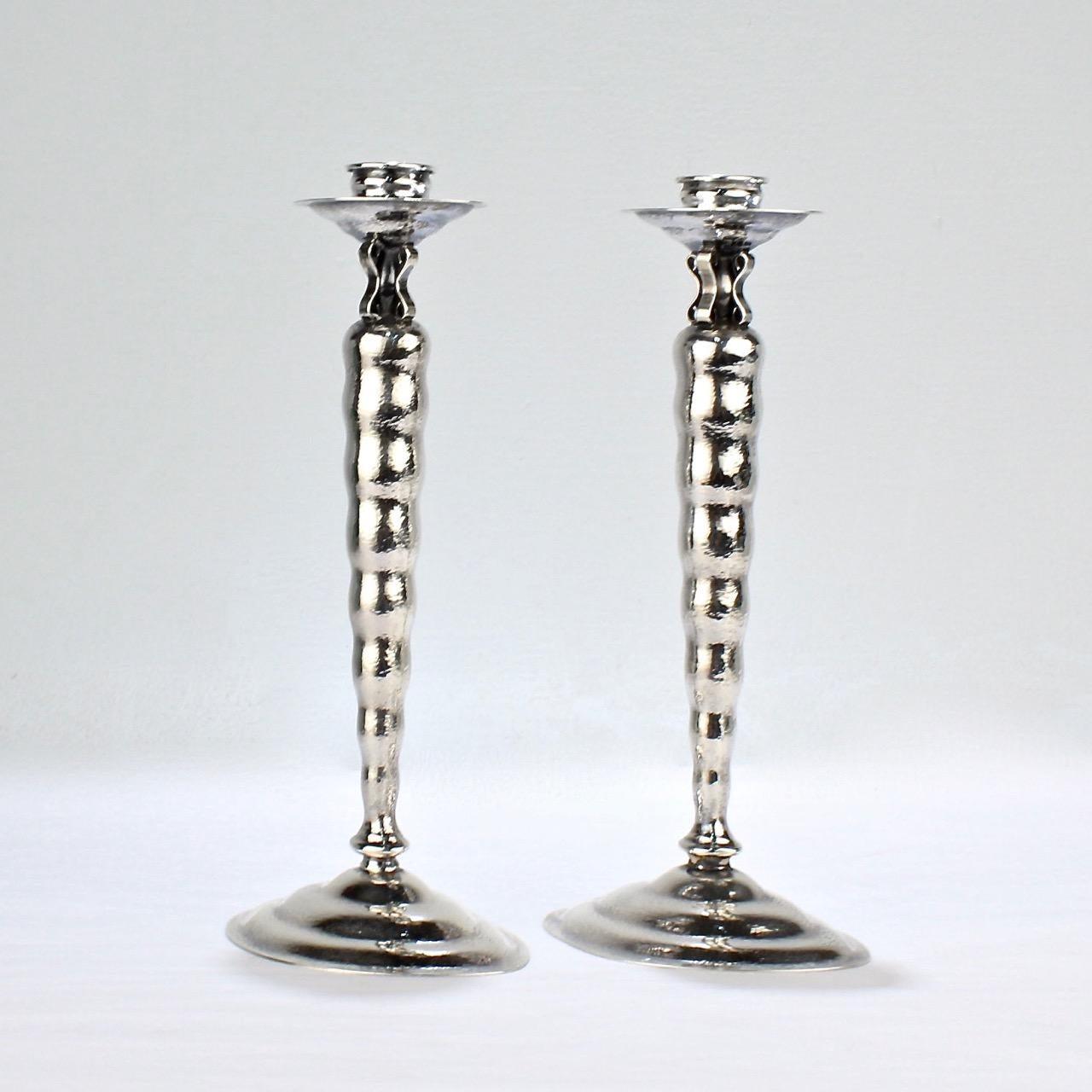 A wonderful pair of Reed & Barton candlesticks.

In the Modernist pattern with a hand hammered finish.

This pair of American Deco candlesticks feature candle cups and bobeches that rest above a tapered, undulating shafts and bases. The undulating