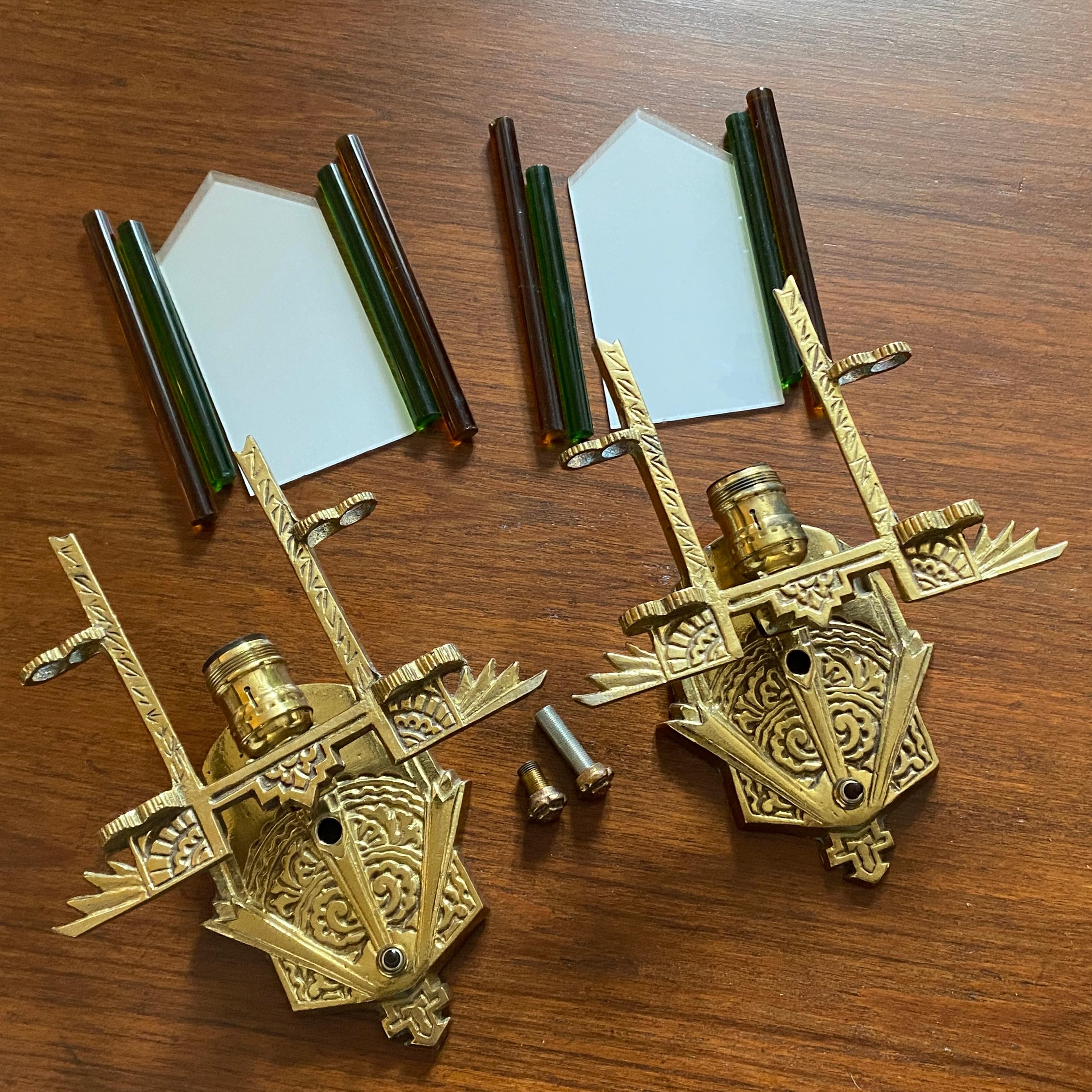 A pair of vintage Art Deco style brass electric wall sconces with white glass shades and orange and green glass rods on either side. Manufacturer unknown. 