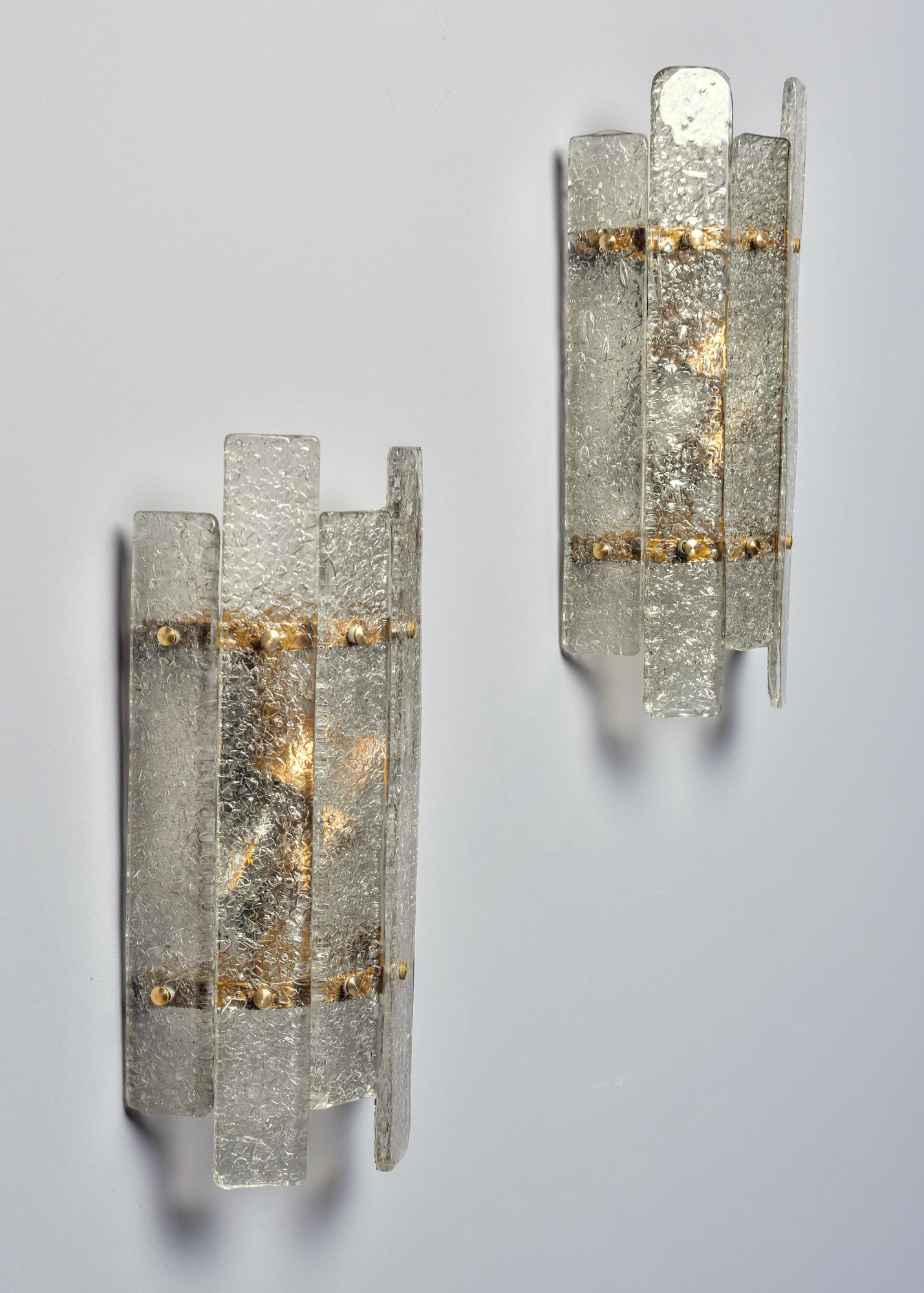Made in Italy, these Deco style sconces have shades comprised of clear textured glass slats and brass hardware. Two standard sized sockets each. Sold and priced as a pair.