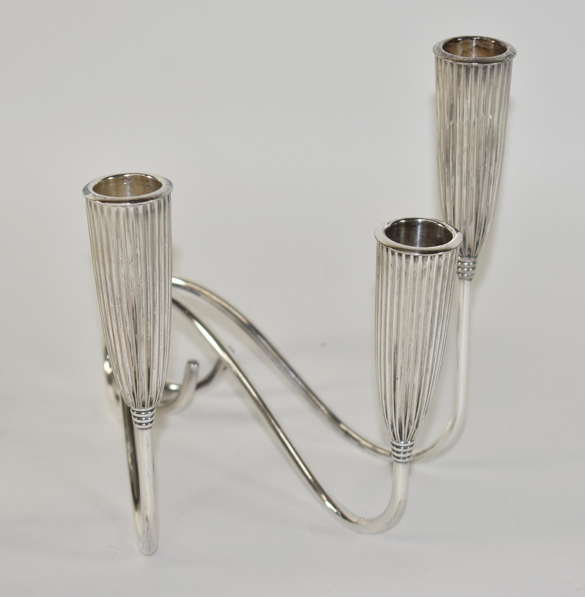 This elegant and graphic pair of sliver plated triple branch candlestick were realized by the celebrated design firm Napier Company in the USA, circa 1910. Features three undulating arms that culminate in fluted bullet form supports. Overall very