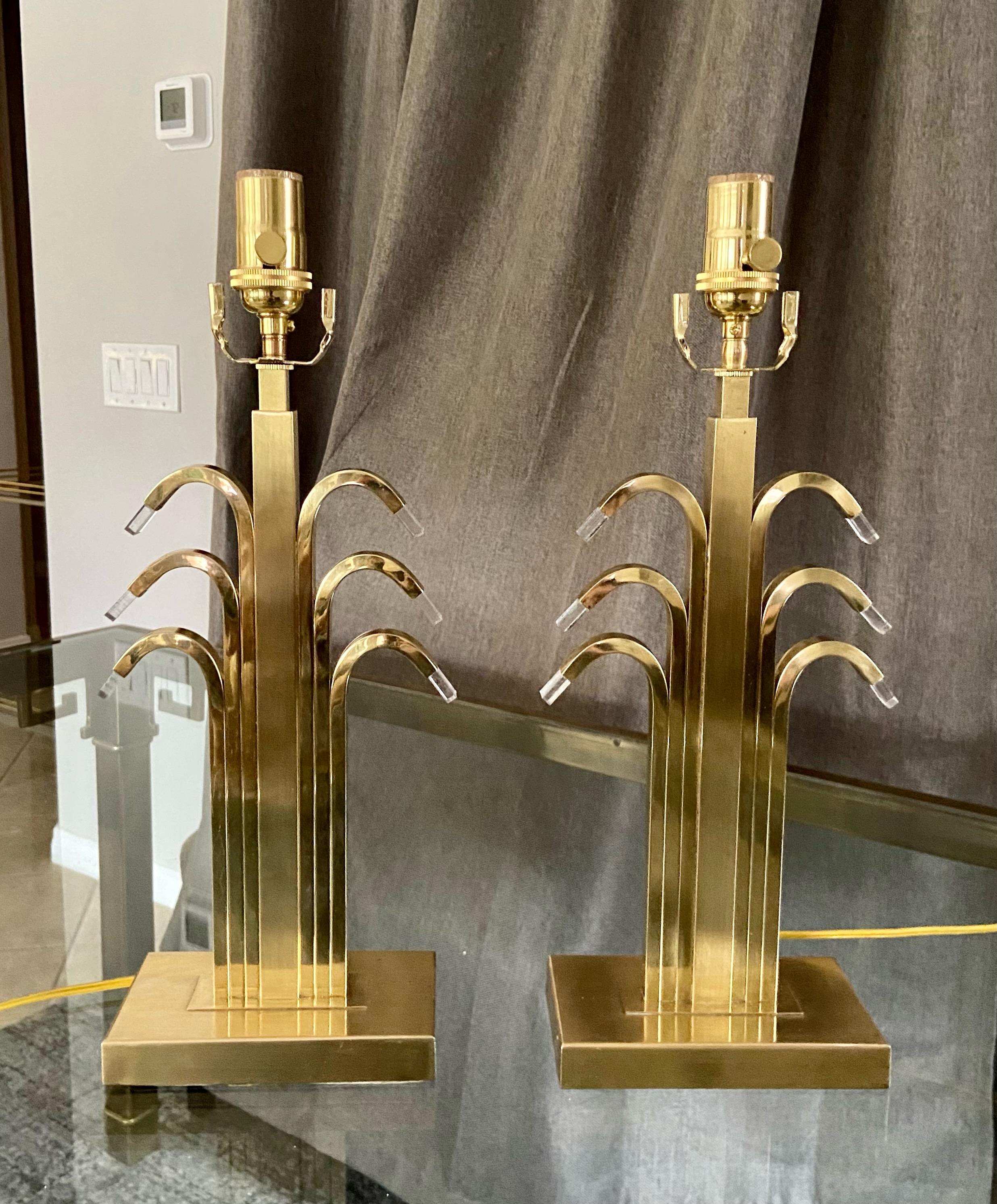 Pair of art deco style brass table lamps each with 6 curved arm waterfall effect. Adding to its unique style each curved arm has an acrylic tip. The brass is solid and and expertly constructed. Newly wired 3 way sockets and cords. Overall height top