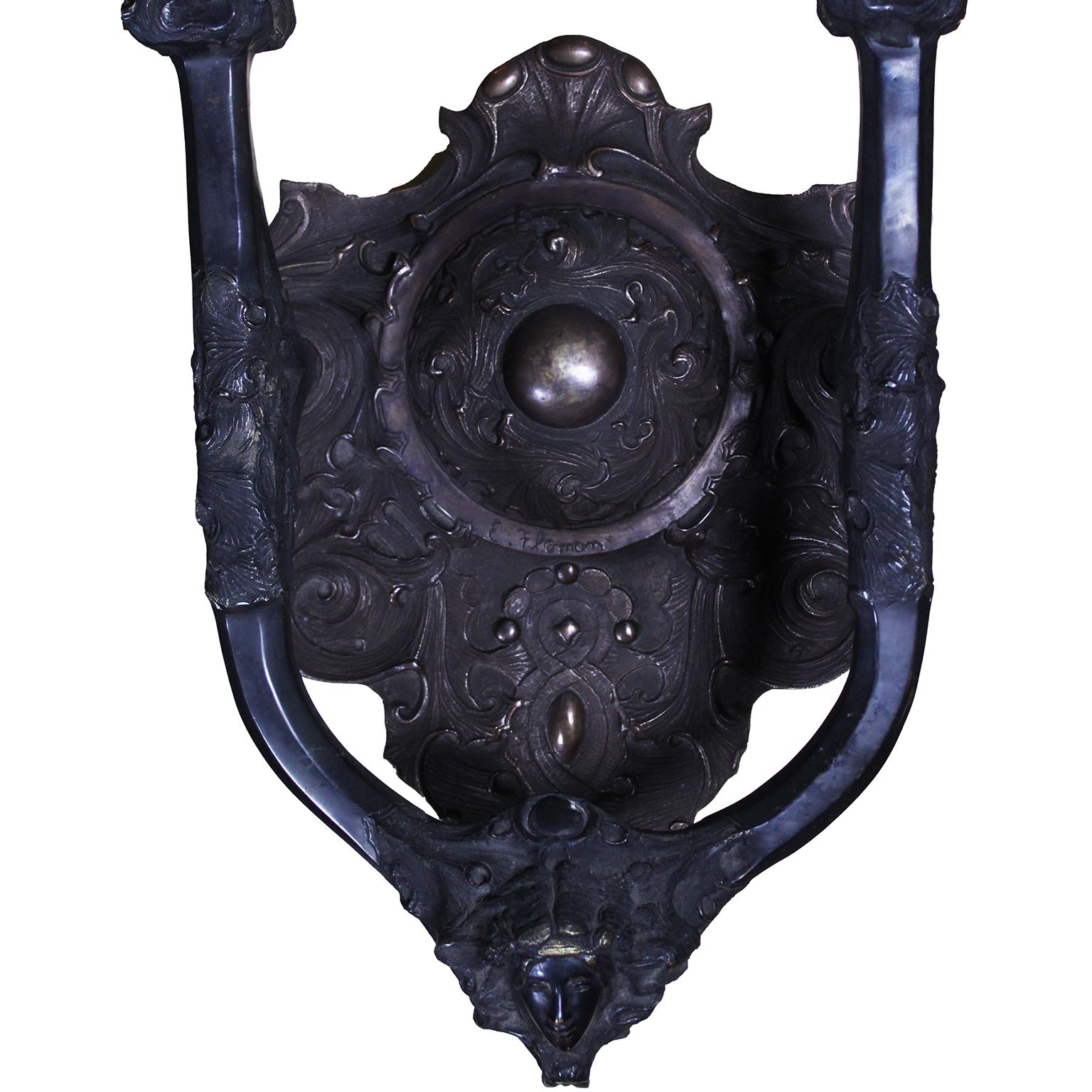 Grande et impressionnante paire d'appliques murales à deux lumières en bronze patiné de style Art-Nouveau, chacune dotée d'un abat-jour en verre clair et centrée sur un masque de jeune fille. Inscrit : Flamand. D'après un modèle de Georges Flamand,