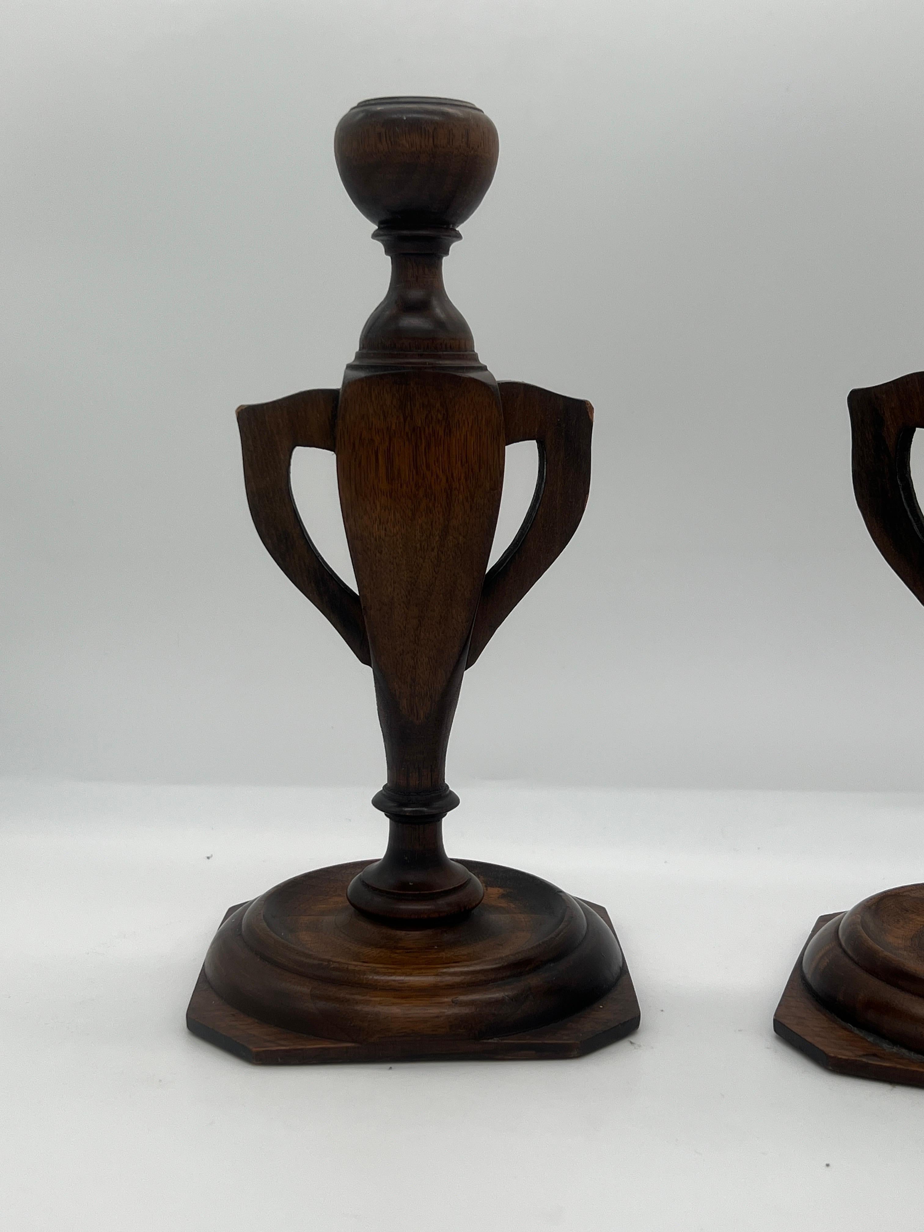 Likely American, circa 1910. 

A pair of carved wood possibly oak or walnut candlesticks in the form of trophy urns. Unmarked. 