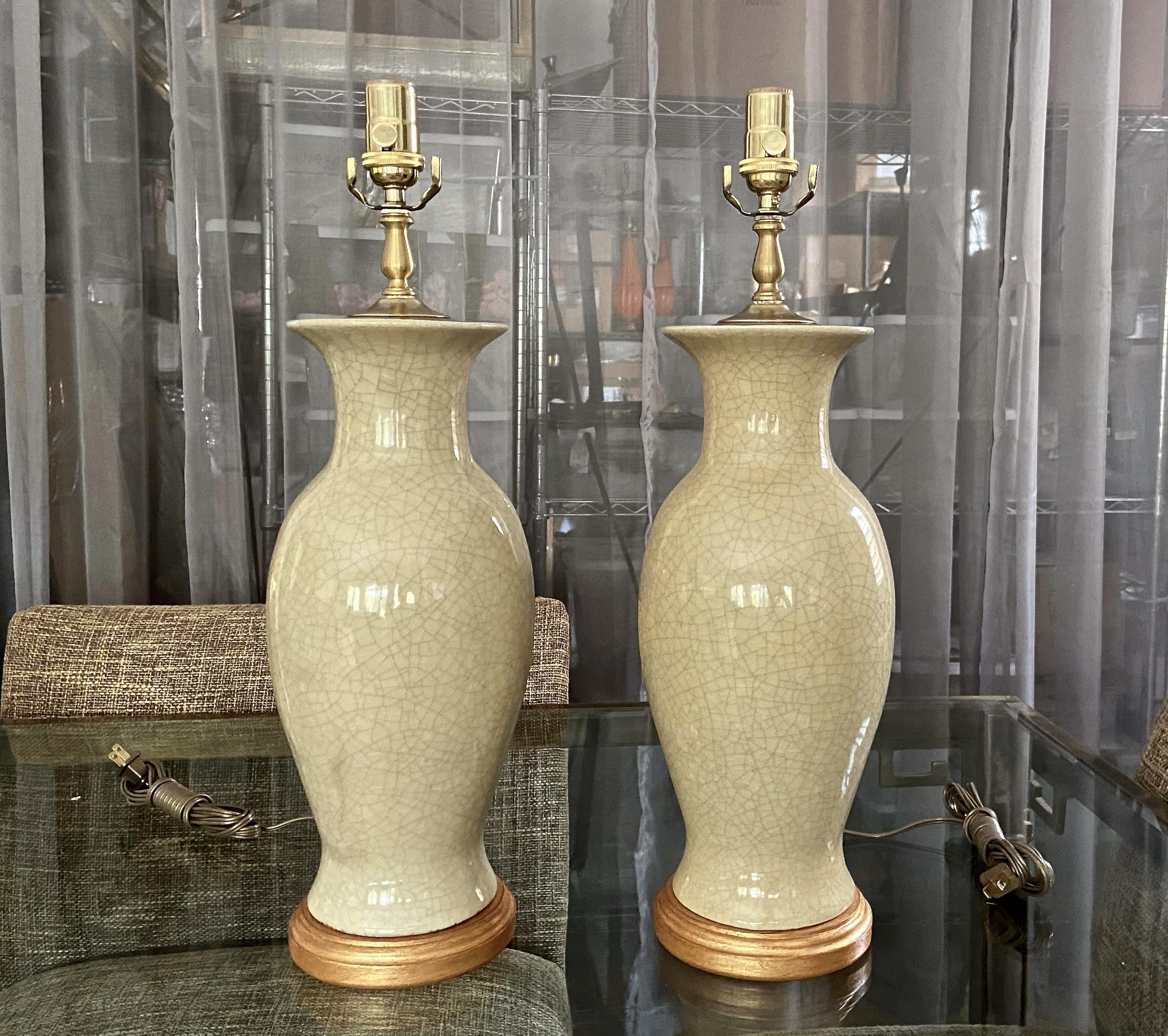 Pair of Chinese pale yellow crackle glaze porcelain baluster form vases table lamps. Each mounted on gilt turned wood lamp bases. Newly wired with brass 3 way sockets. Porcelain vase portion is 15