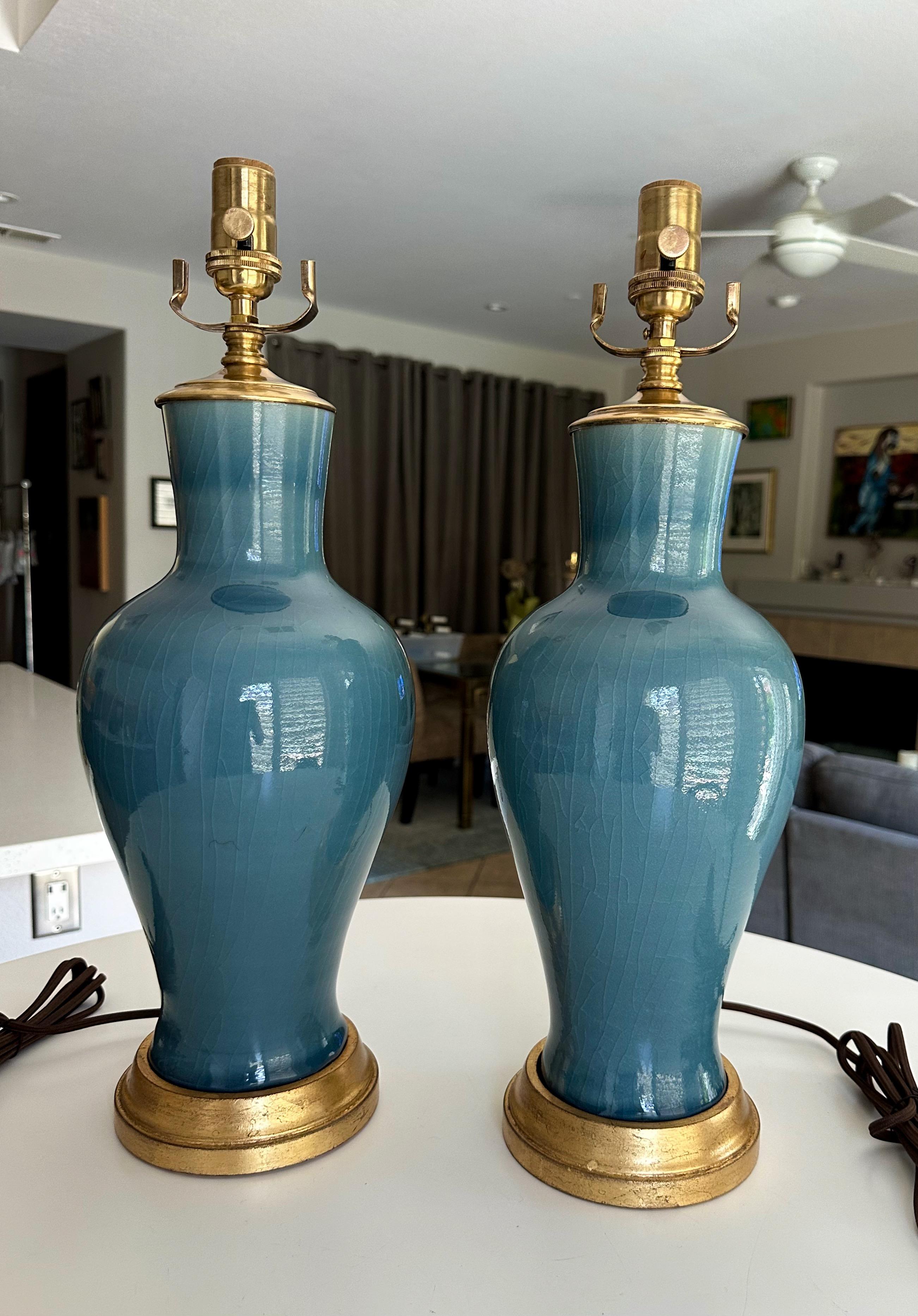 Paire de lampes de table chinoises en porcelaine gris-bleu. Chacune est montée sur des socles en bois doré. Le câblage a été refait à neuf avec des prises à 3 voies en laiton et des cordons en rayonne. Les lampes mesurent 20,5