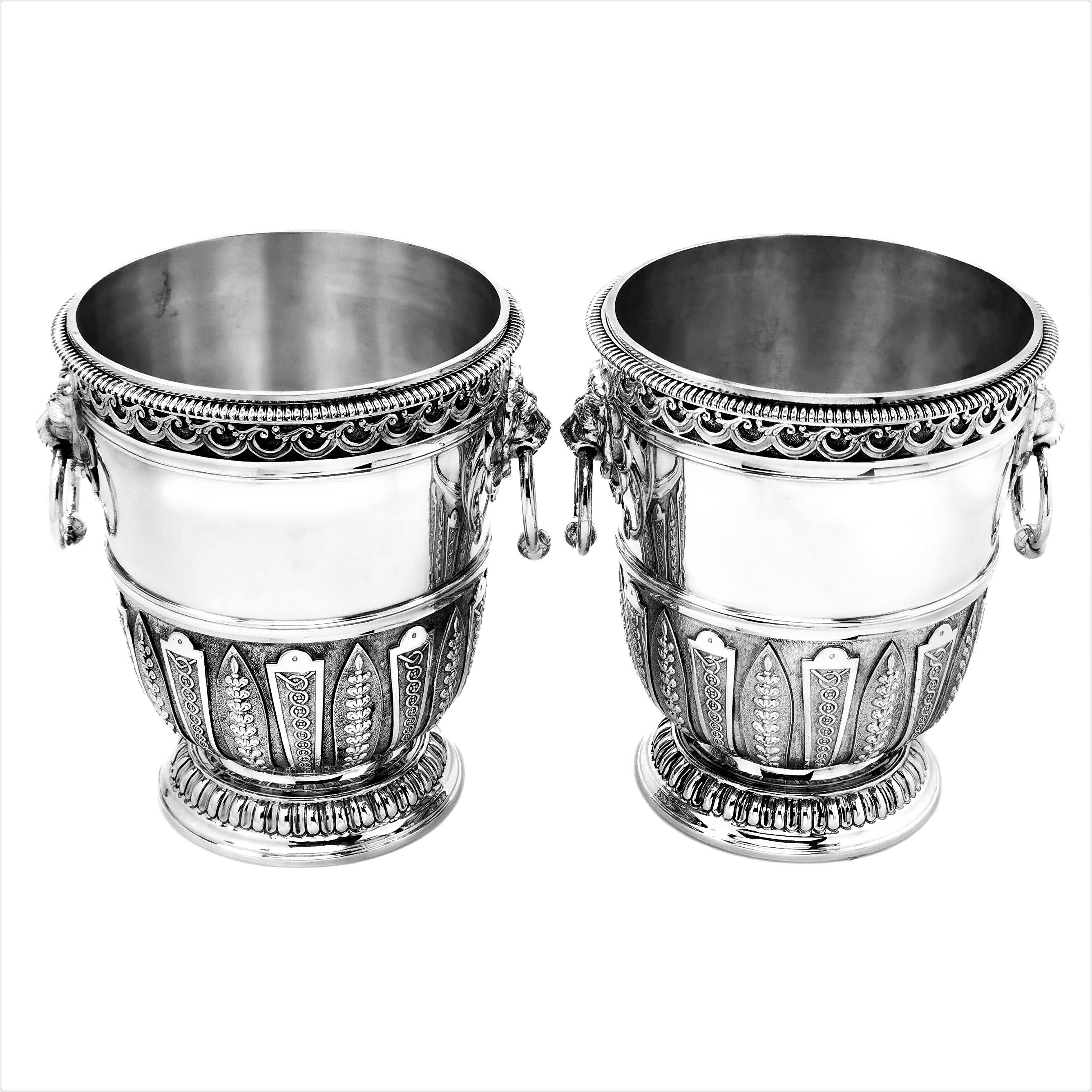A pair of magnificent solid Silver Champagne Coolers / Wine Buckets each with a pair of impressive lion head handles. Each Champagne Bucket is further embellished with repeating chased designs around the body and below the upper rim. The Coolers