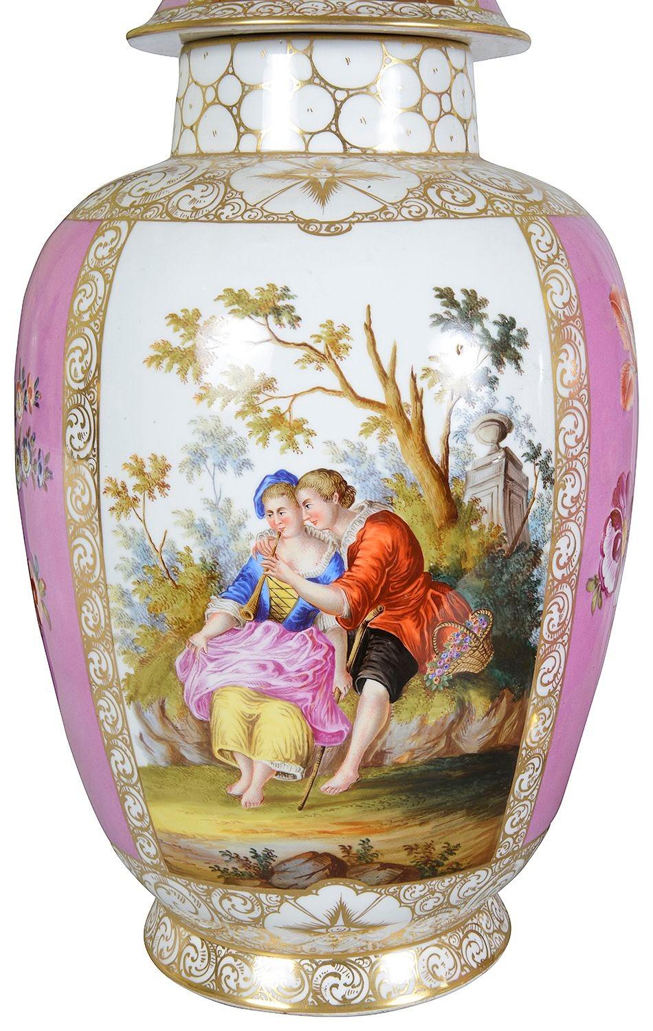 Una coppia molto decorativa di vasi con coperchio in porcellana tedesca del XIX secolo di Augustas Rex. Ognuno di essi presenta un fondo rosa, bordi dorati a volute, pannelli dipinti a mano che raffigurano amanti che si corteggiano nei